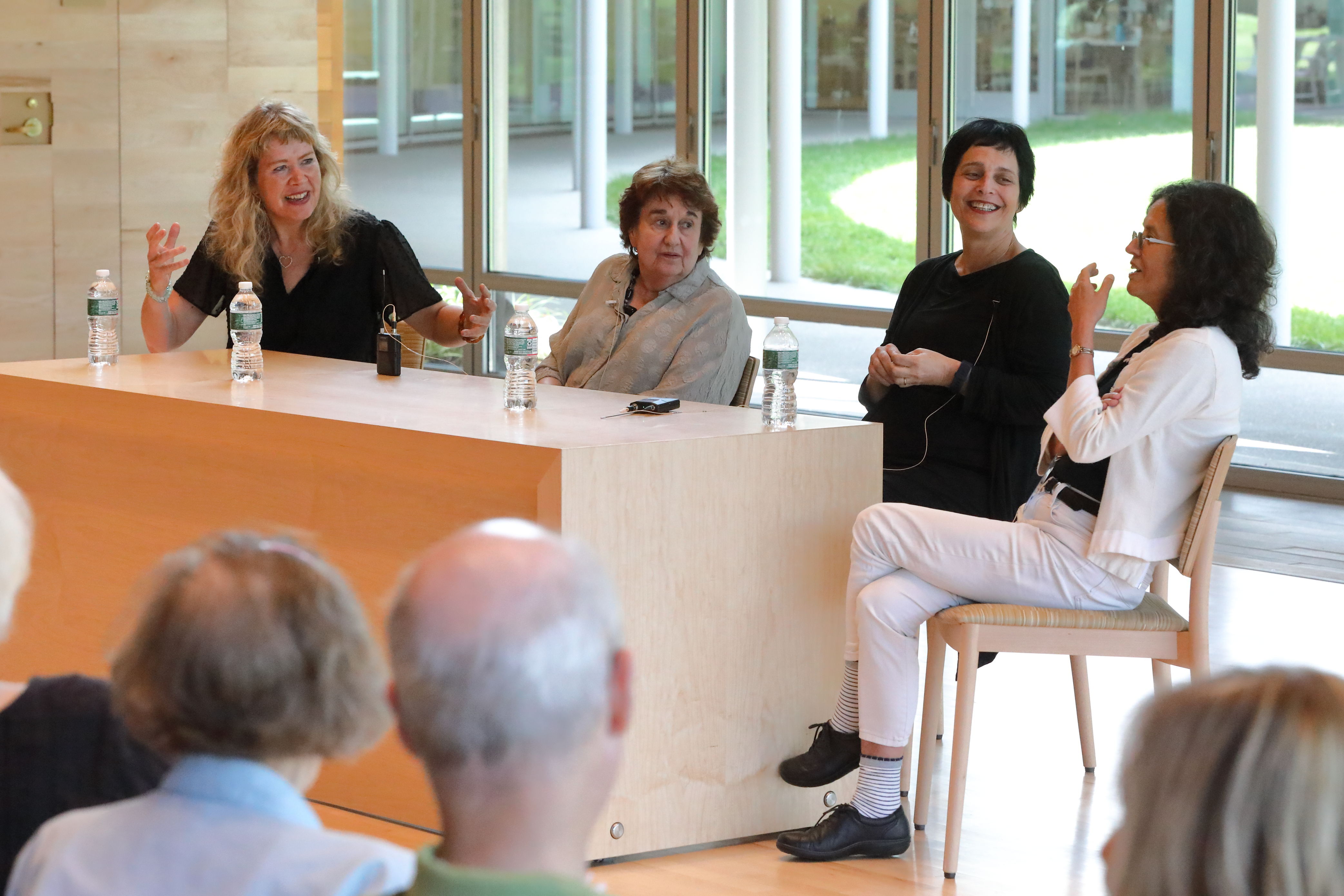 Four women sit at a long table in the Linde Center's Studio E, smiling and talking