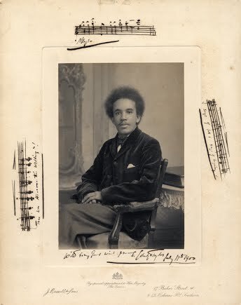 Portrait of Samuel Coleridge-Taylor seated in a chair, with musical fragments inscribed on the border