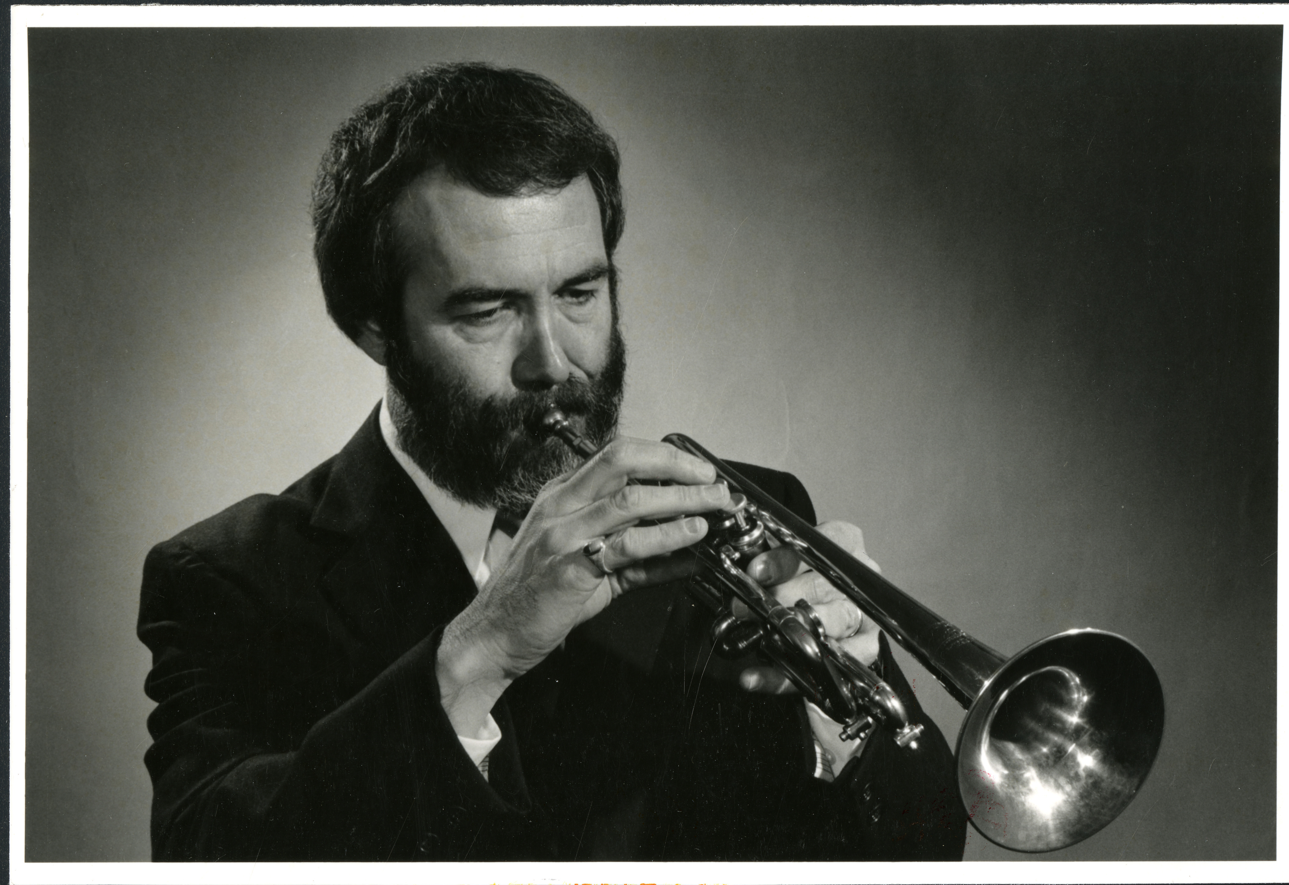 Headshot of bearded man playing the trumpet
