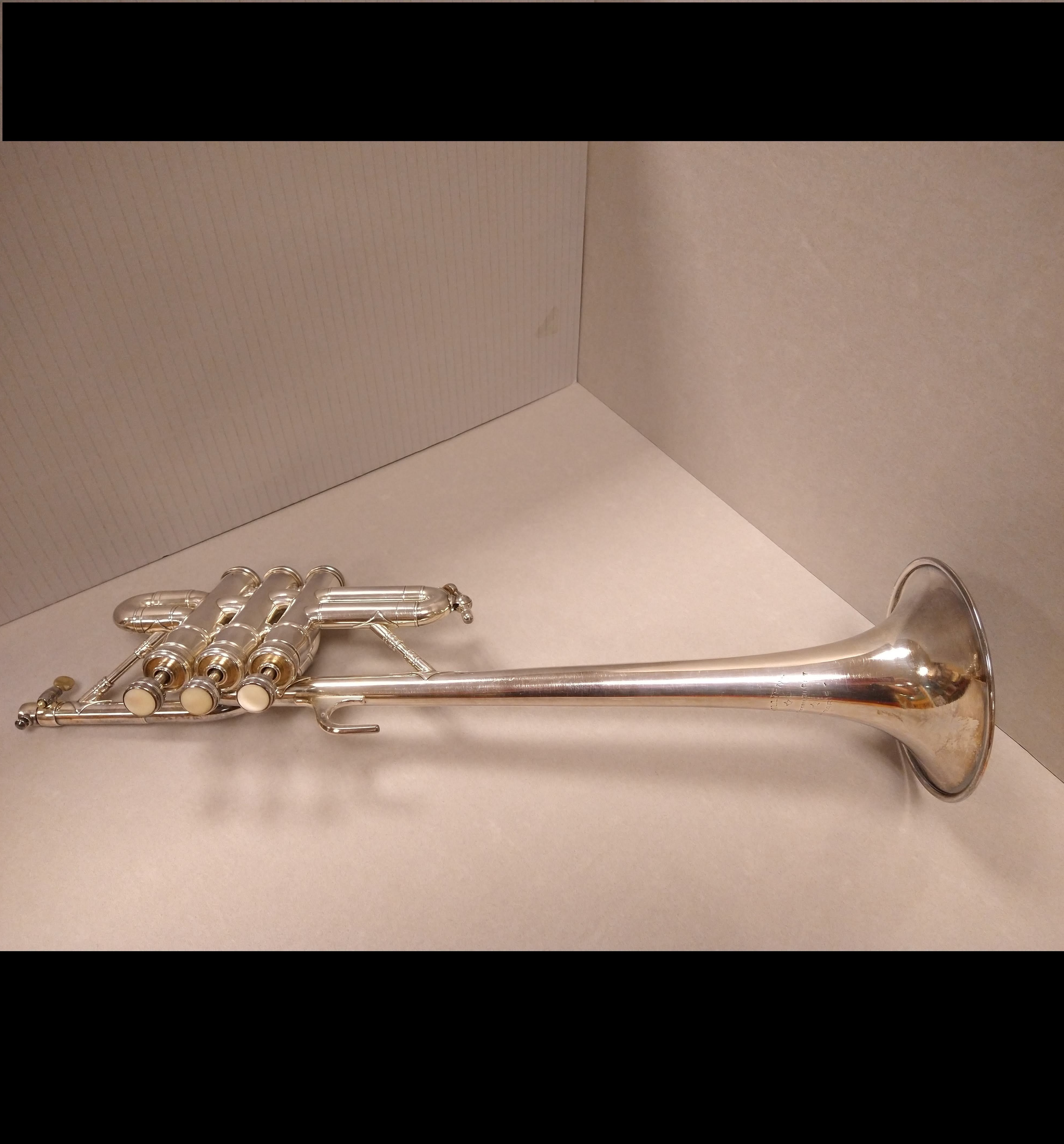Image of a silver piccolo trumpet on its side