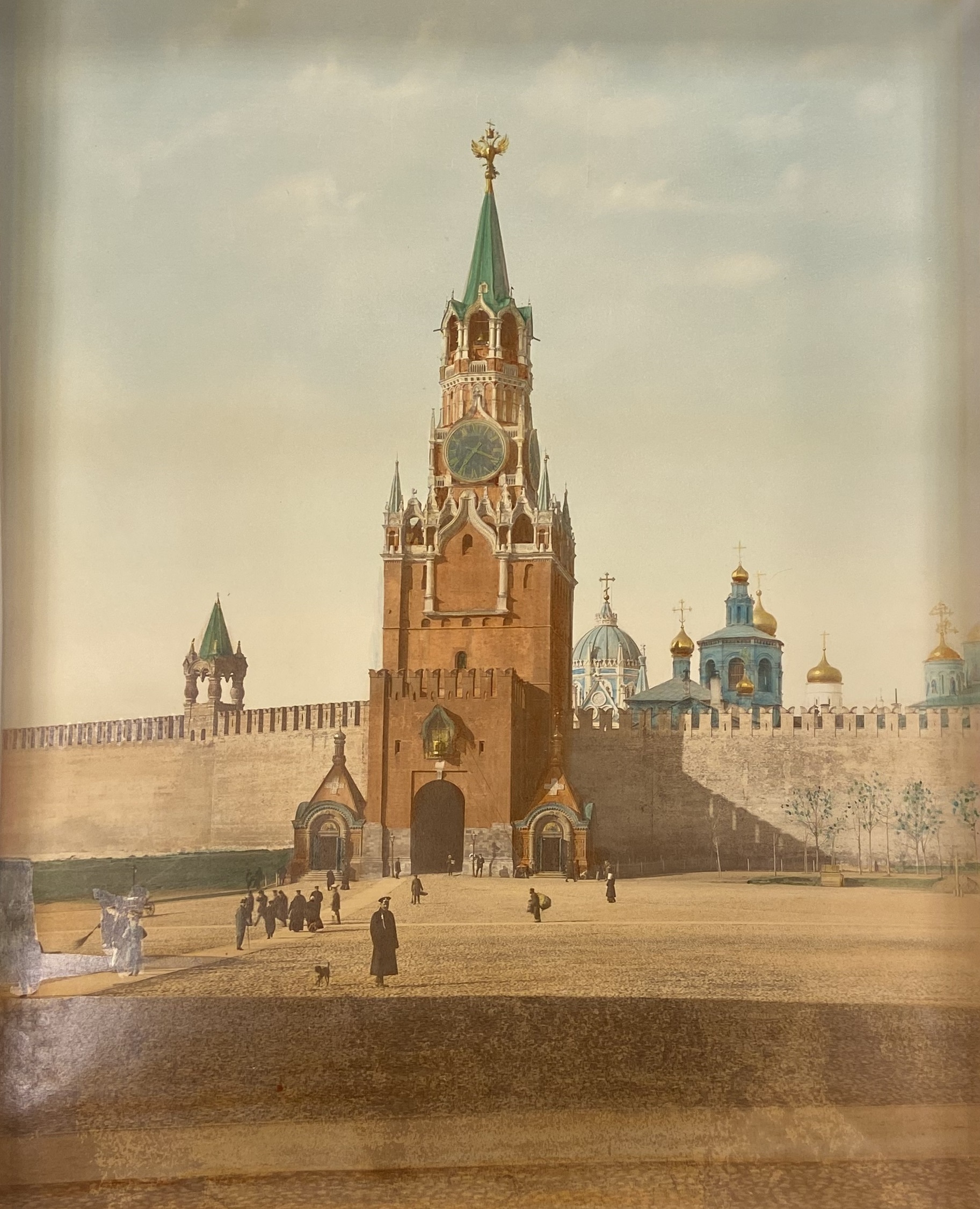 A large clock tower stands in a wall surrounding a square