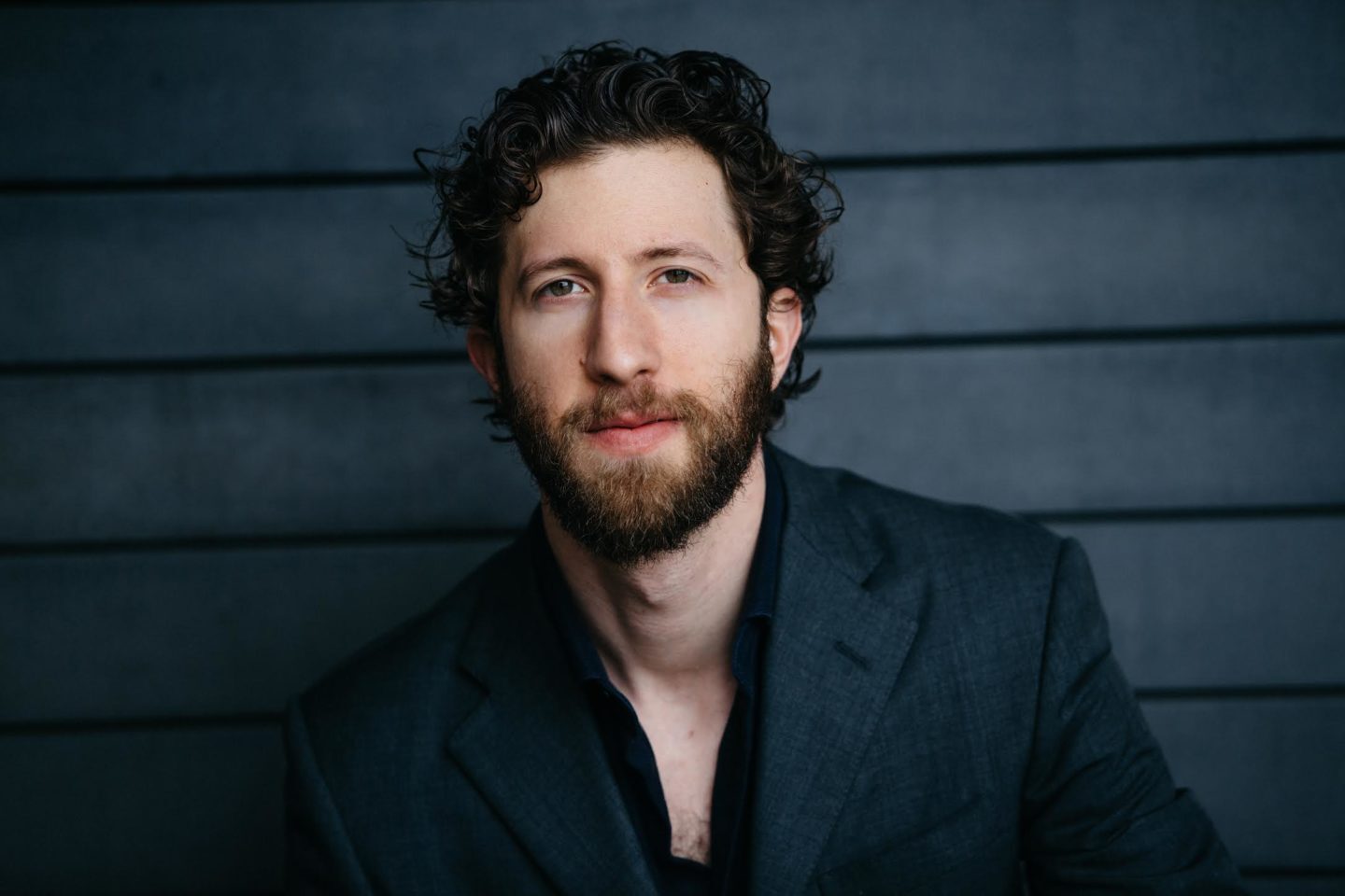 Headshot of David Leigh wearing a dark shirt and suit jacket.