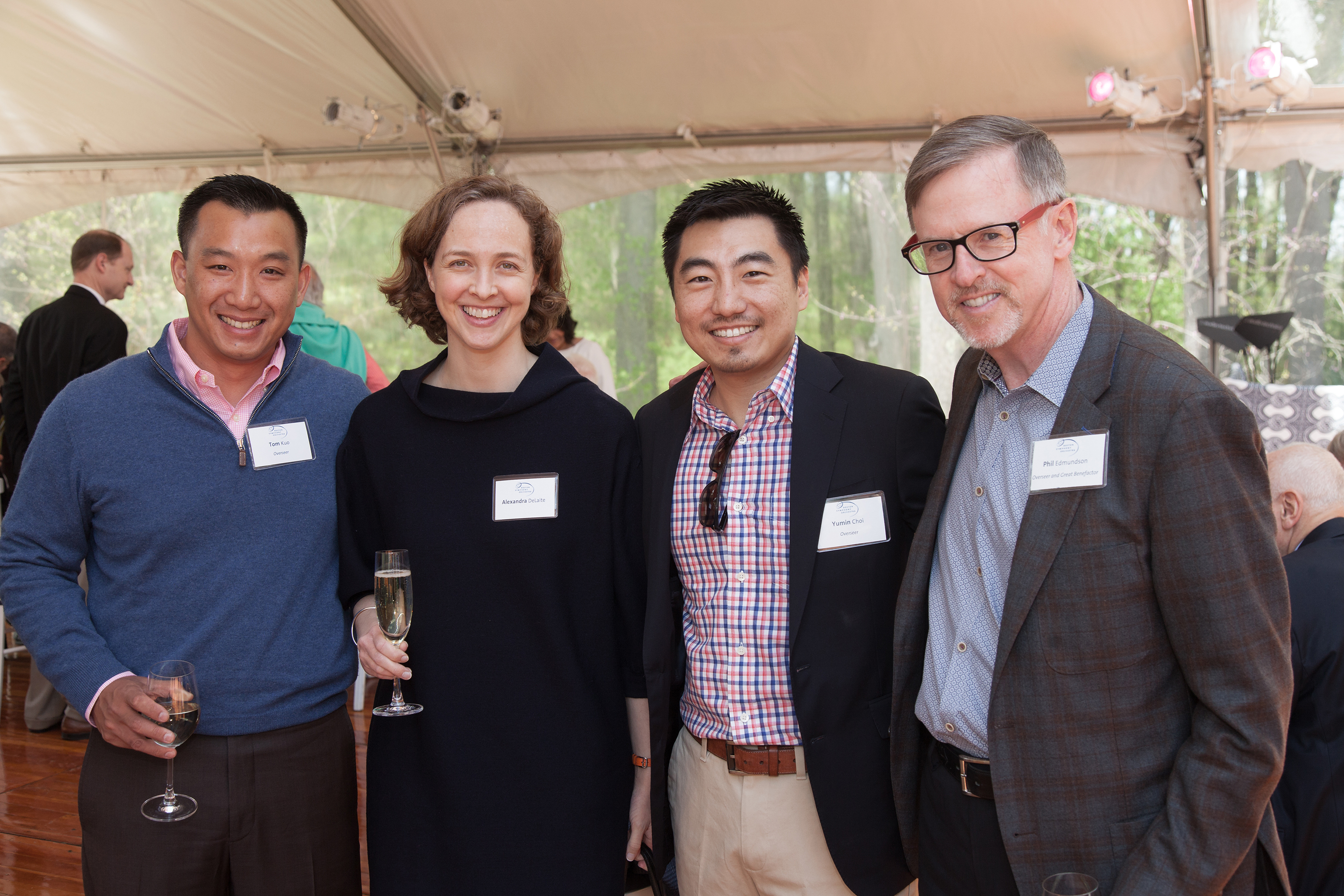 Four people stand in a large event tent and smile at the camera