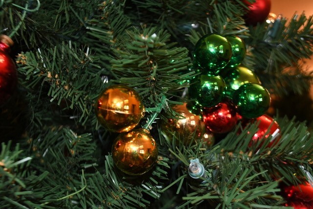 A close-up of the decorations on one of the Christmas trees, featuring red and gold bulbs against the green branches