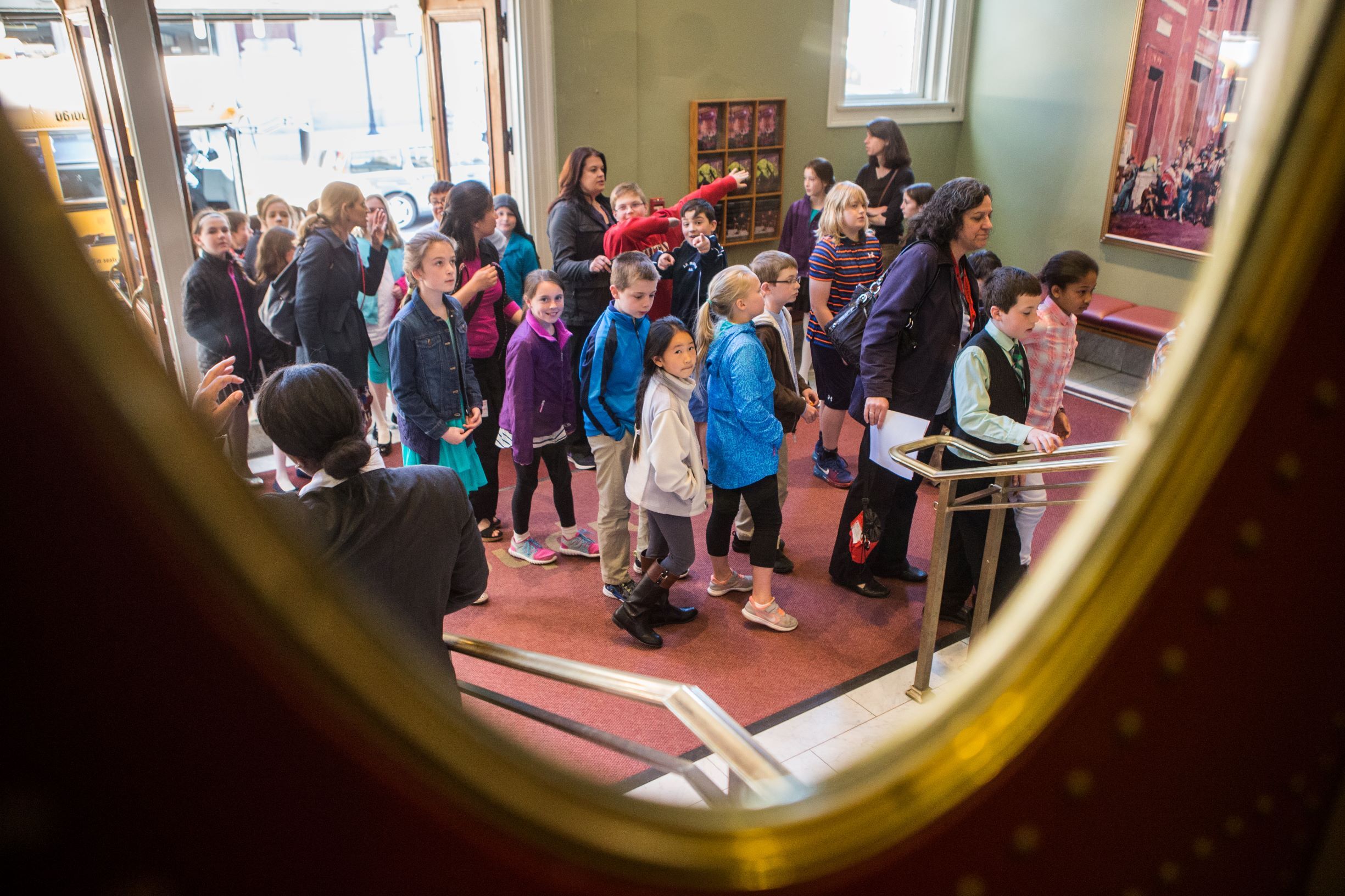 Students and their teacher enter the Symphony Hall lobby. You can see their bus in the background.