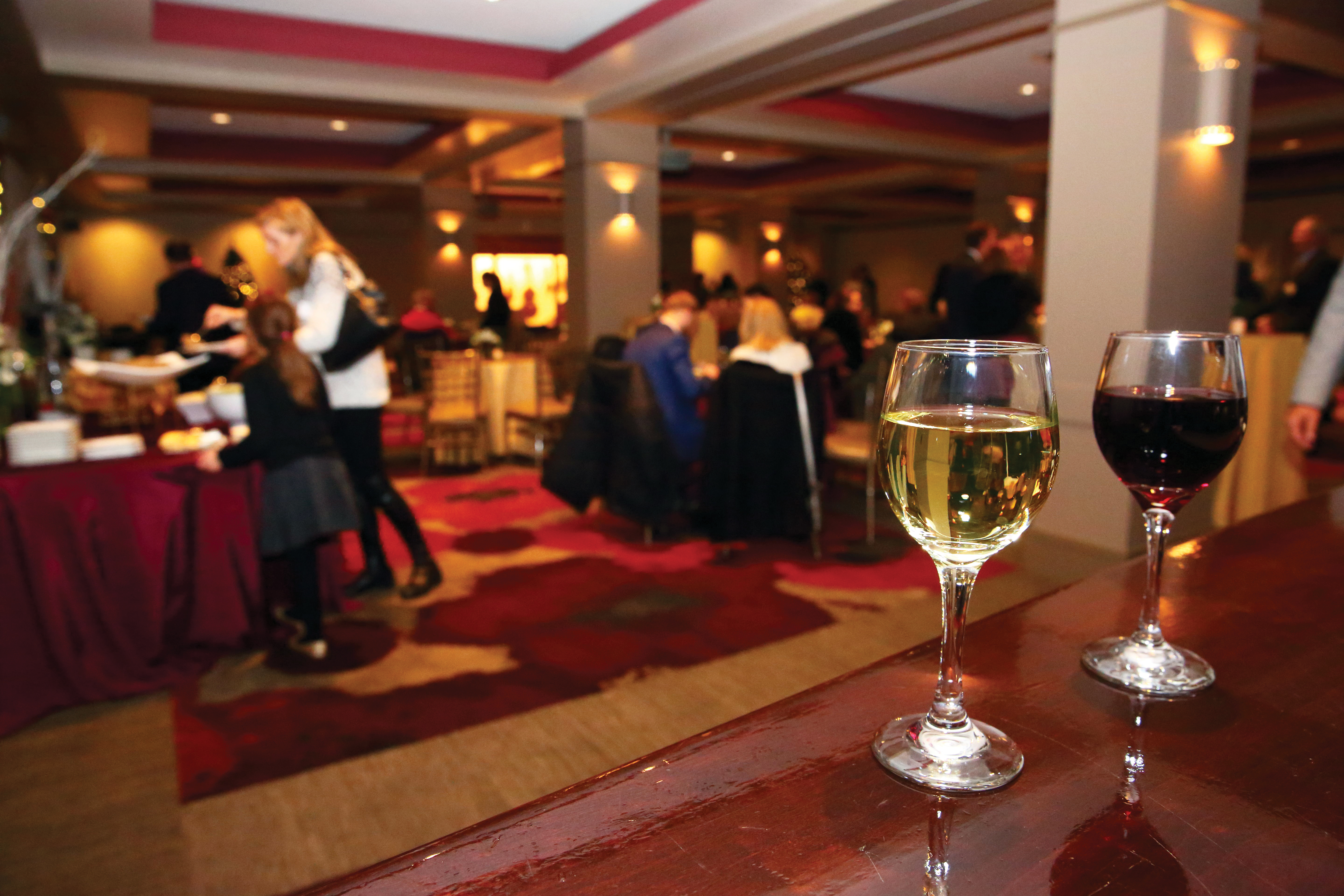 A glass of white wine and a glass of red wine set on a shiny wooden table
