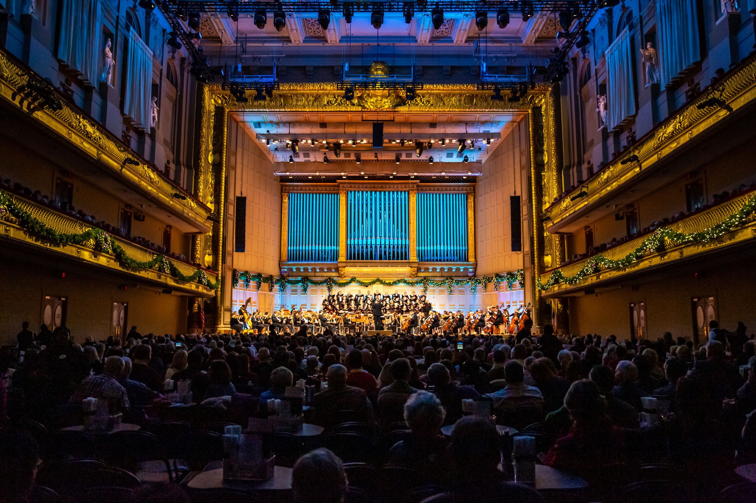 The Holiday Pops audience looks toward the stage which is lit up blue.