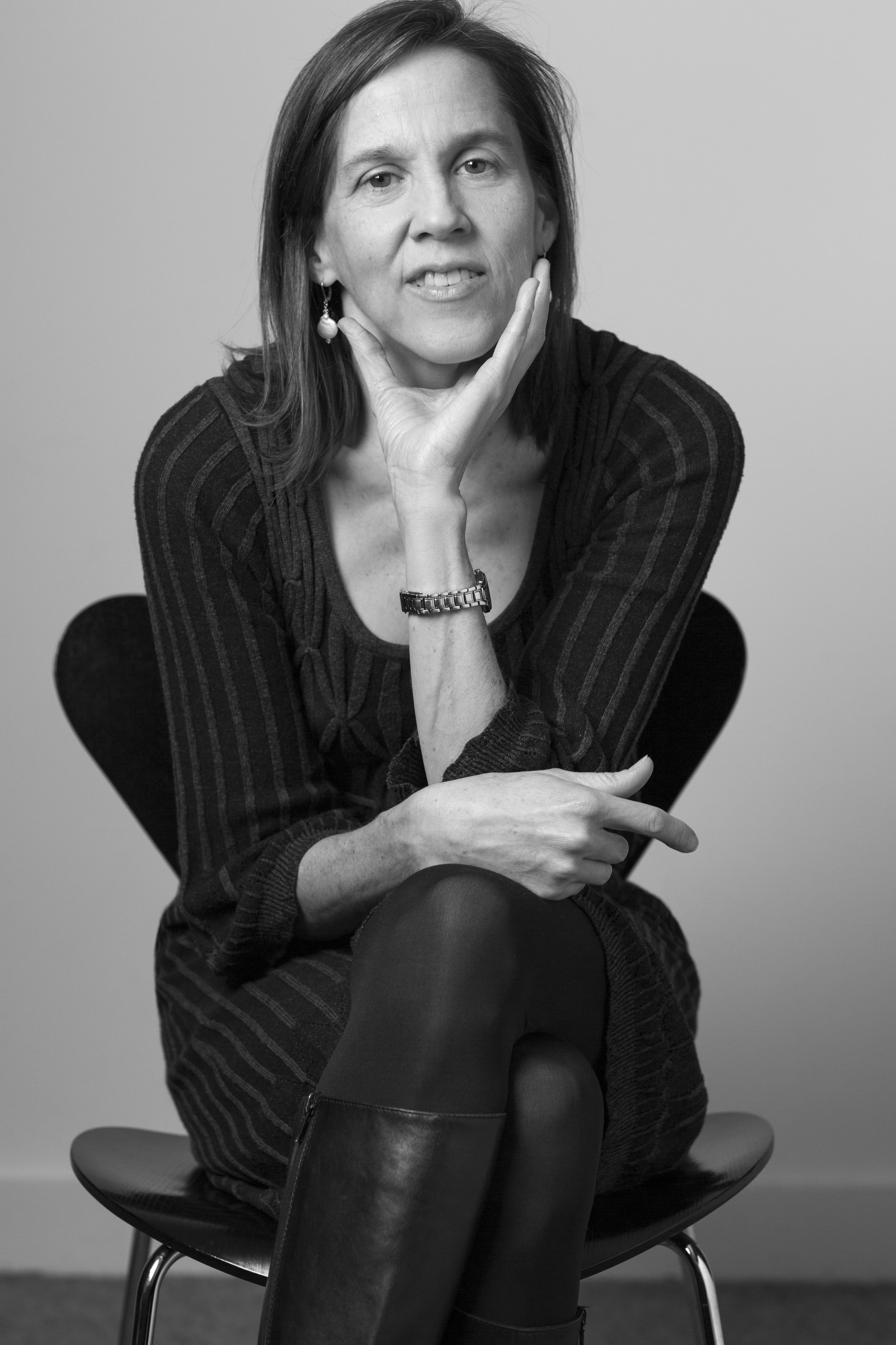 Black and white photo of Jennifer Homans sitting in a chair resting her chin on her hand