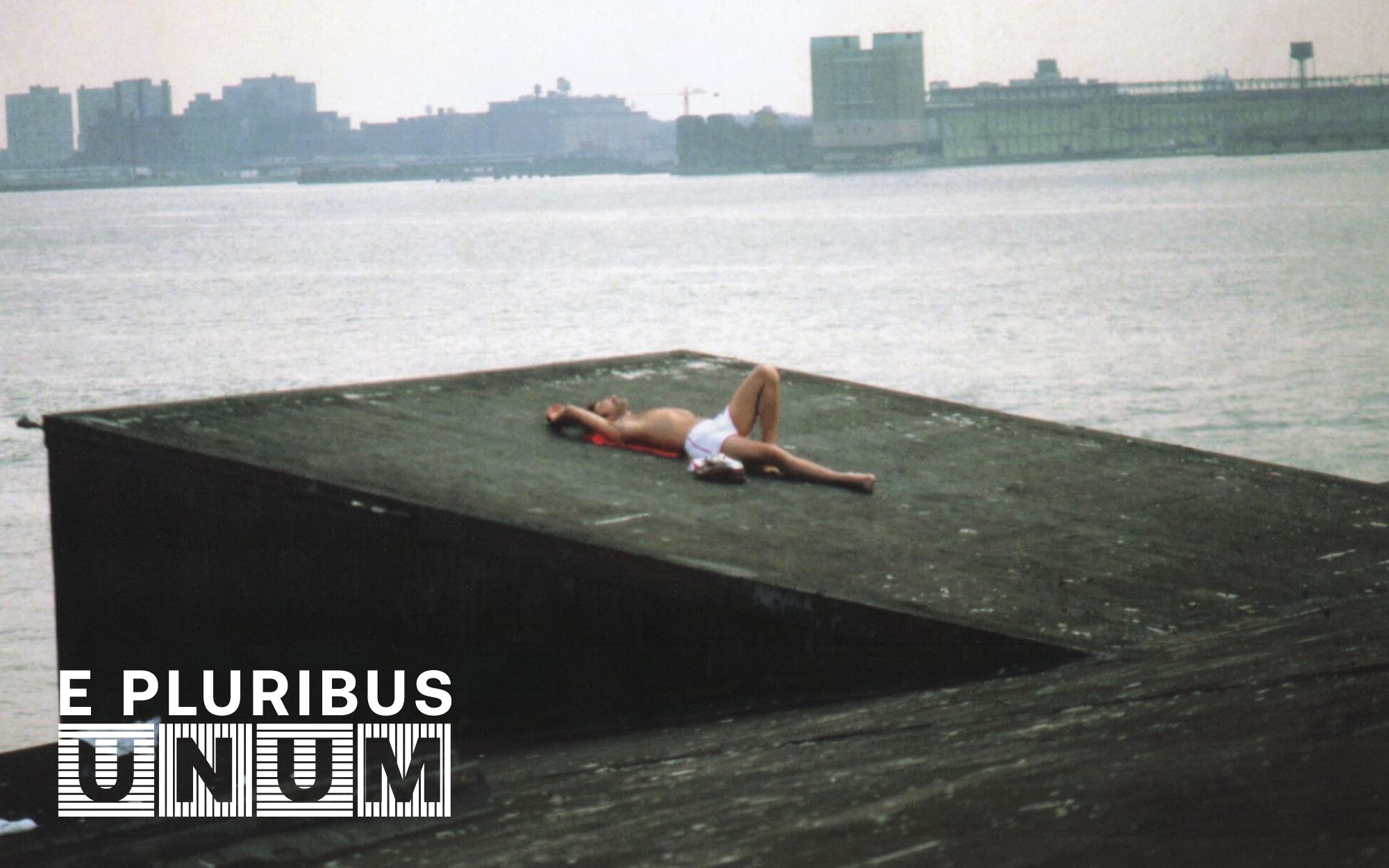 A person lays out on the roof of a building near a river in New York City