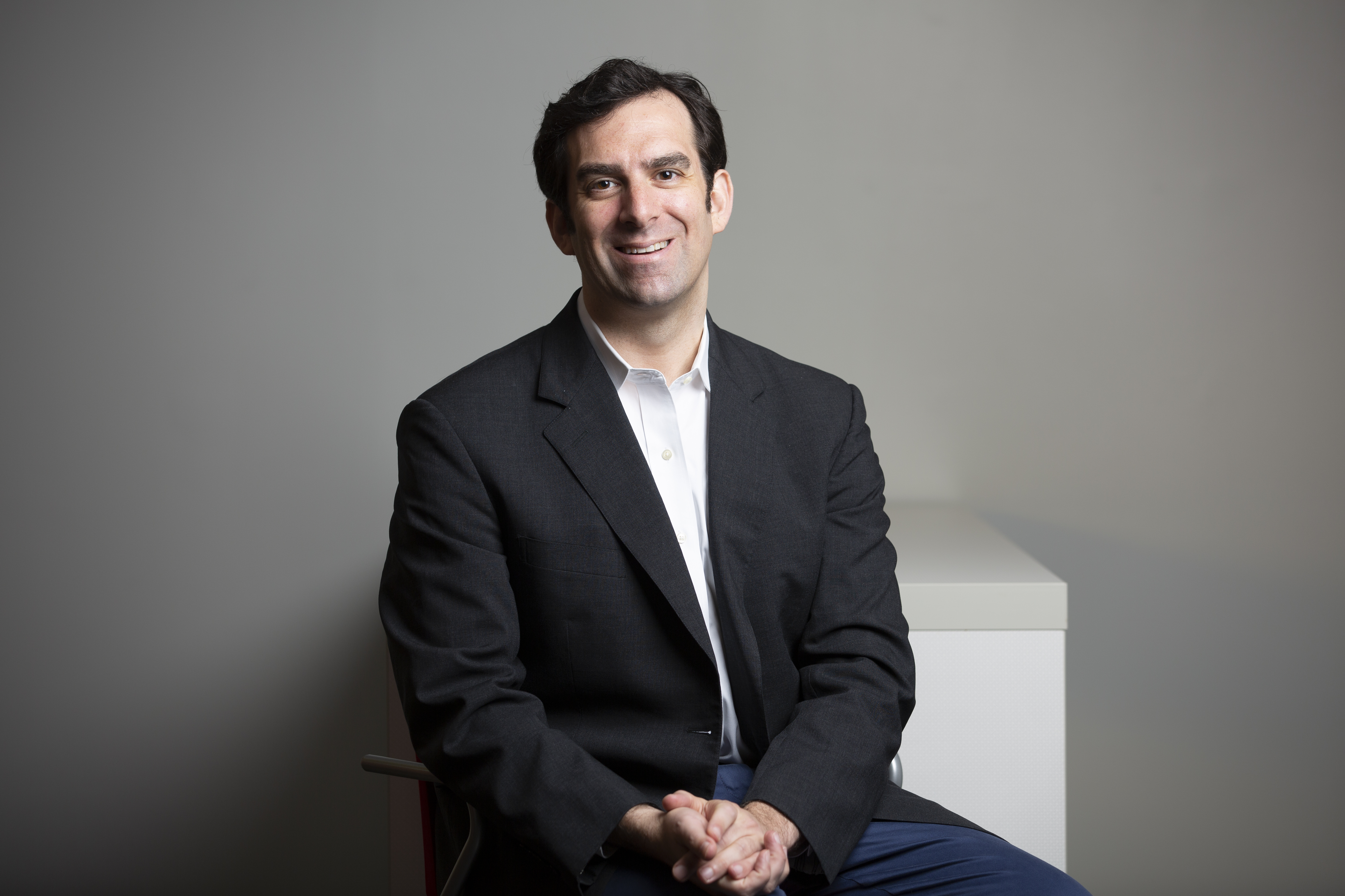 Jeremy Faust, sitting wearing a dark sport jacket with his hands folded in his lap.