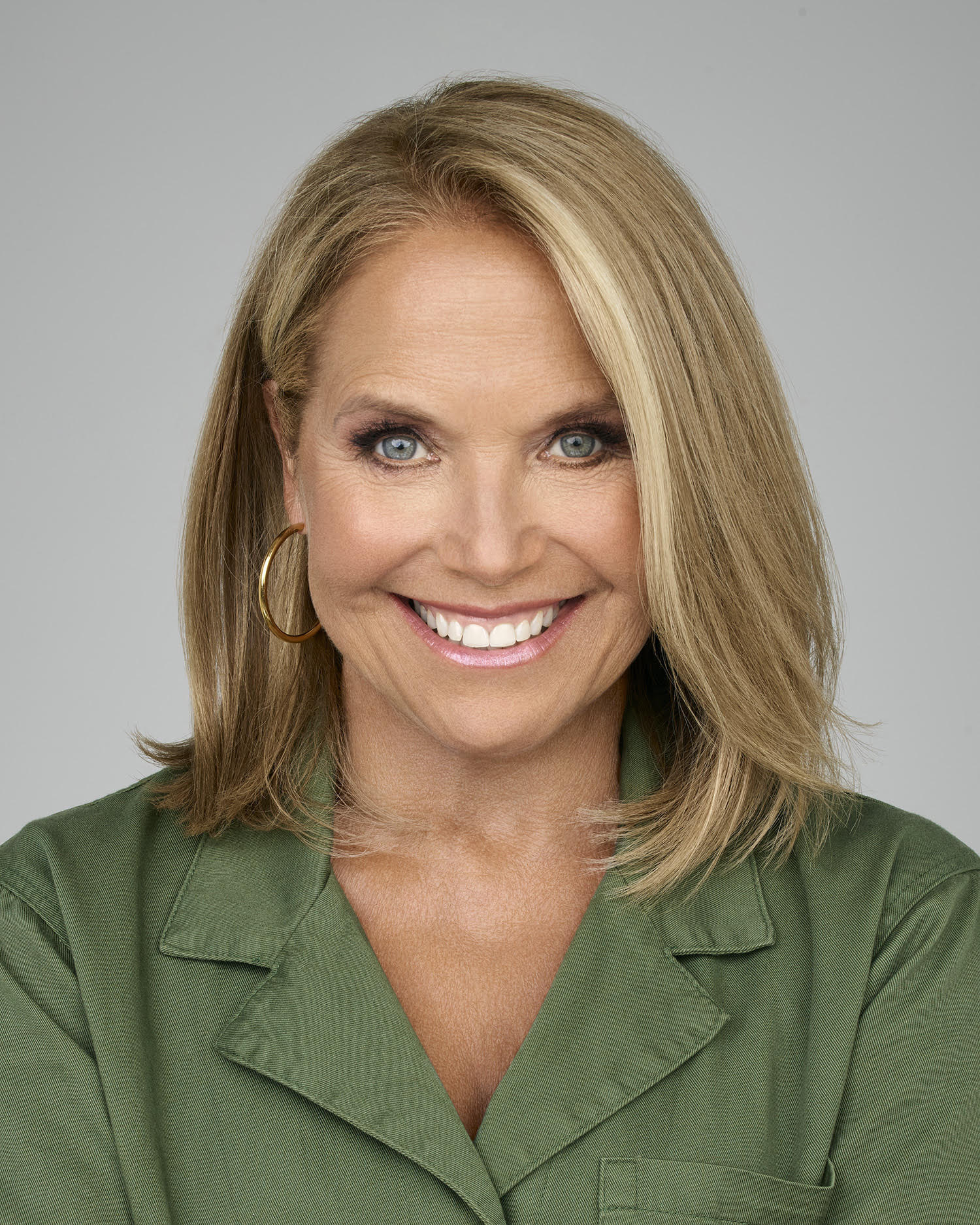 Katie Couric smiling and wearing a green top.