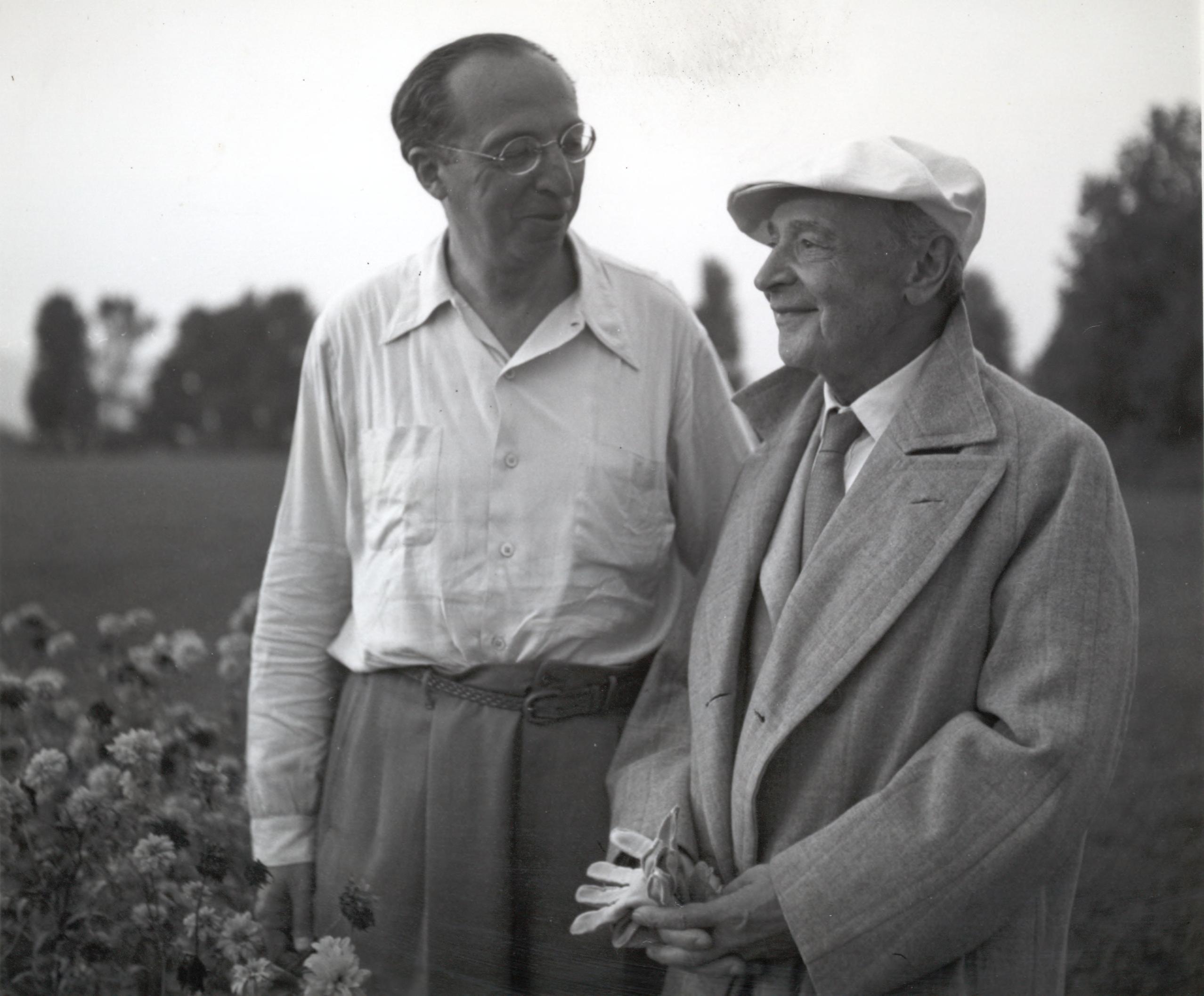 Composer Aaron Copland looks at Serge Koussevitzky, wearing a coat, cap, and gloves