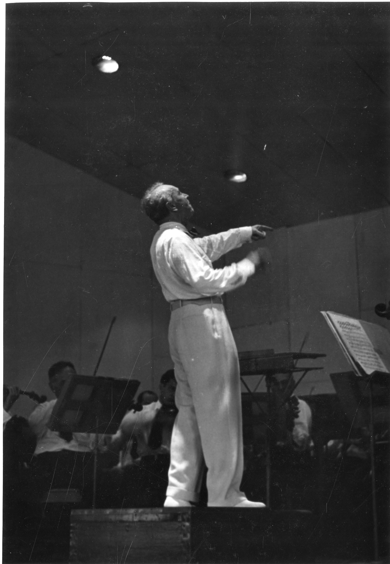 Photo of Serge Koussevitzky dress in white on the conductor's podium, leading the BSO in the Music Shed