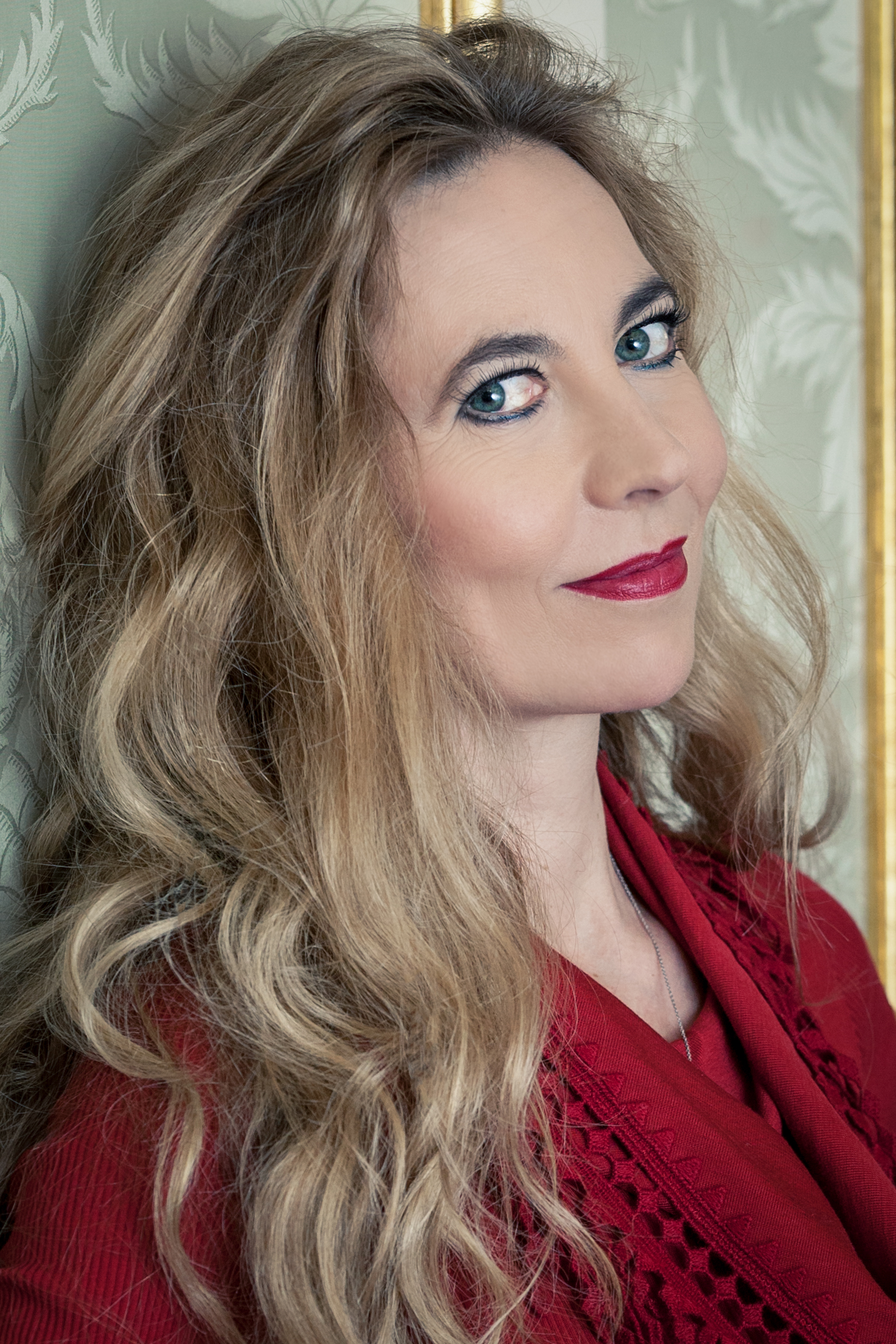 Headshot of Marina Prudenskaya wearing a red shirt and looking at the camera over her shoulder.