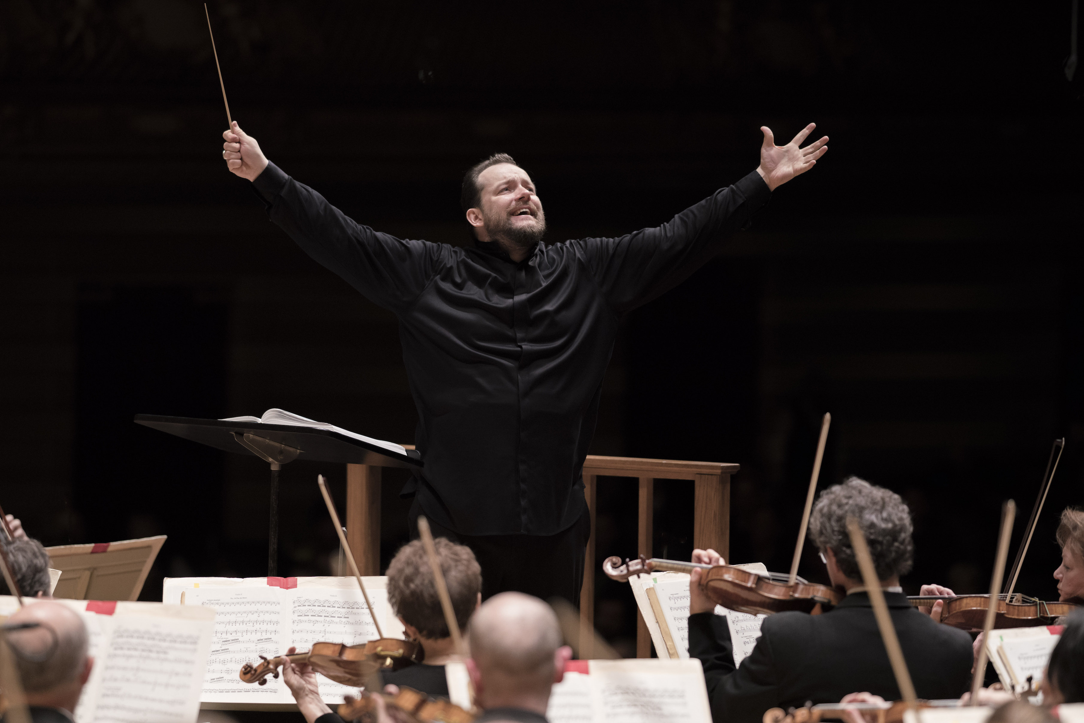 Andris Nelsons conducting, with his arms up and smiling