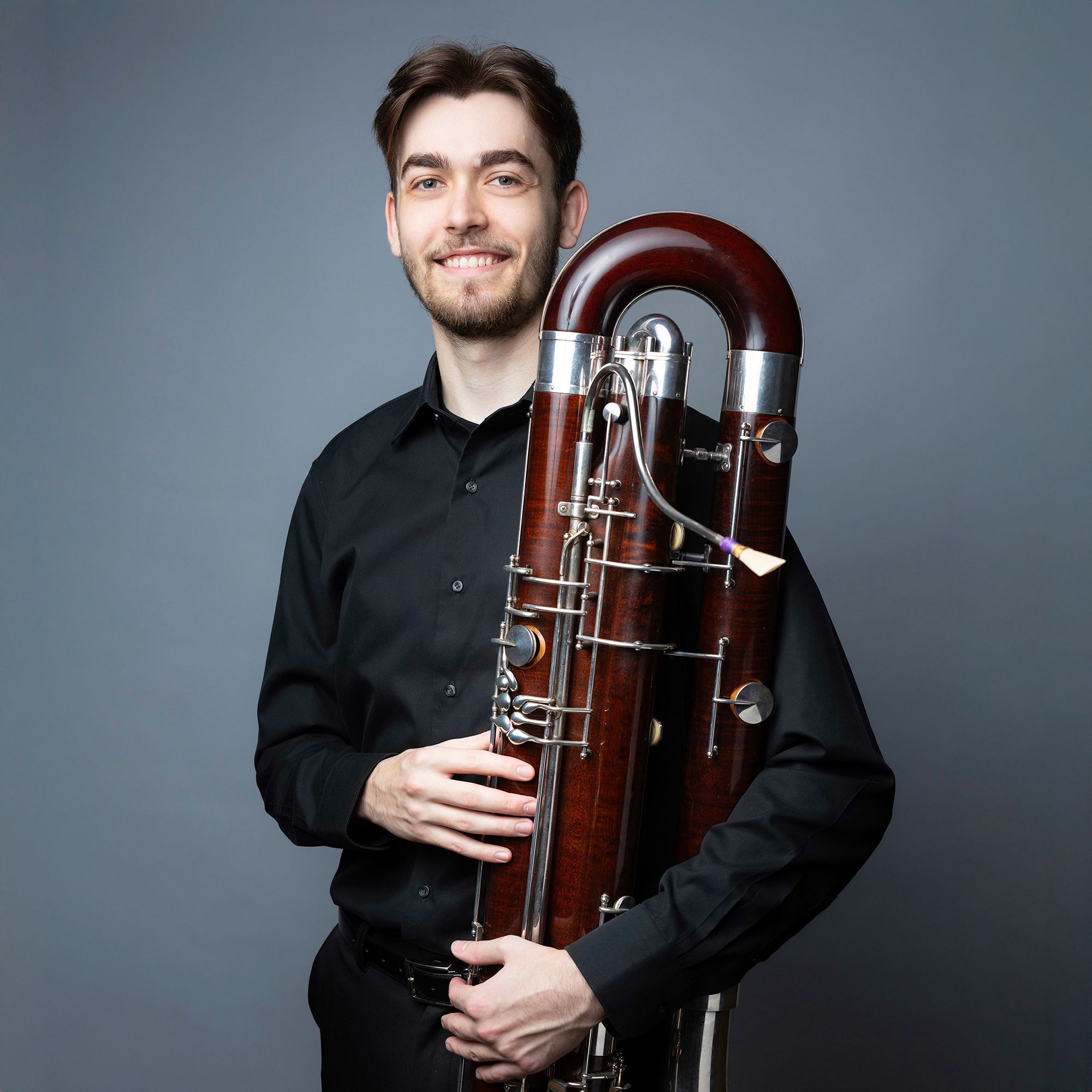 Samuel Watson headshot holding a contrabassoon