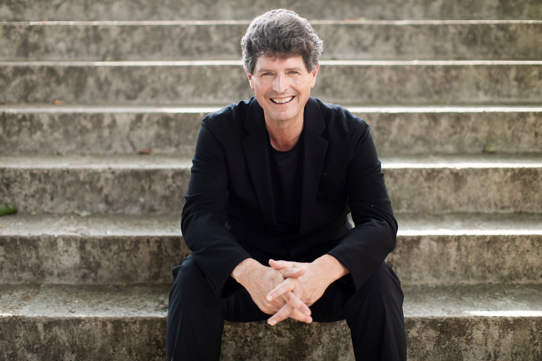 Clark Rundell sitting on stairs with a big smile