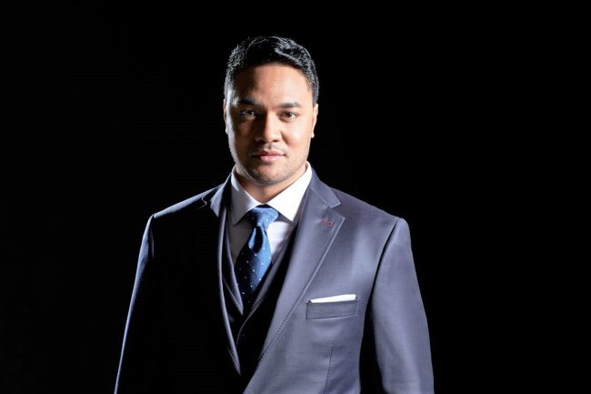 Headshot of Amitai Pati in a grey suit with a black background