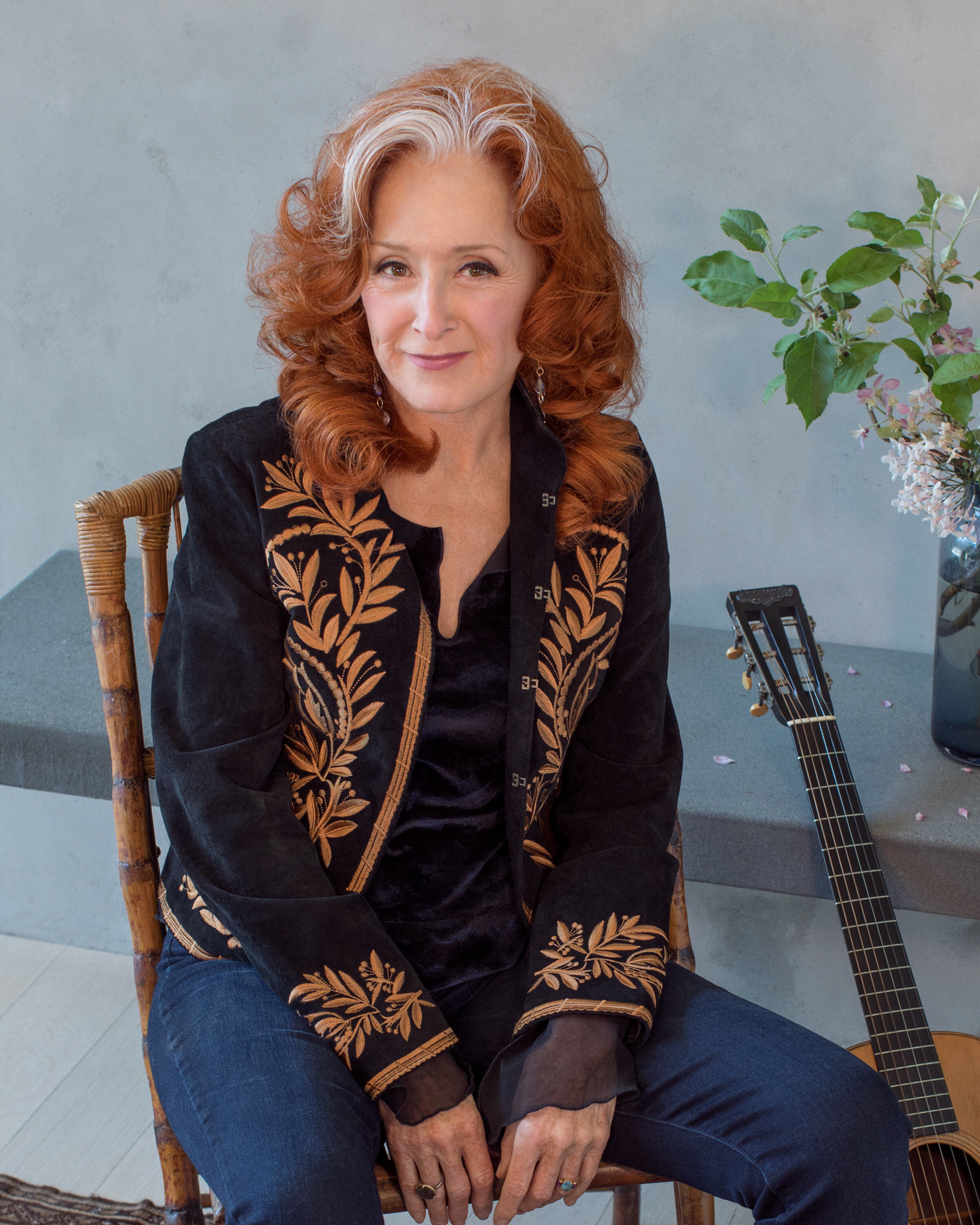 Bonnie Raitt sitting next to an acoustic guitar