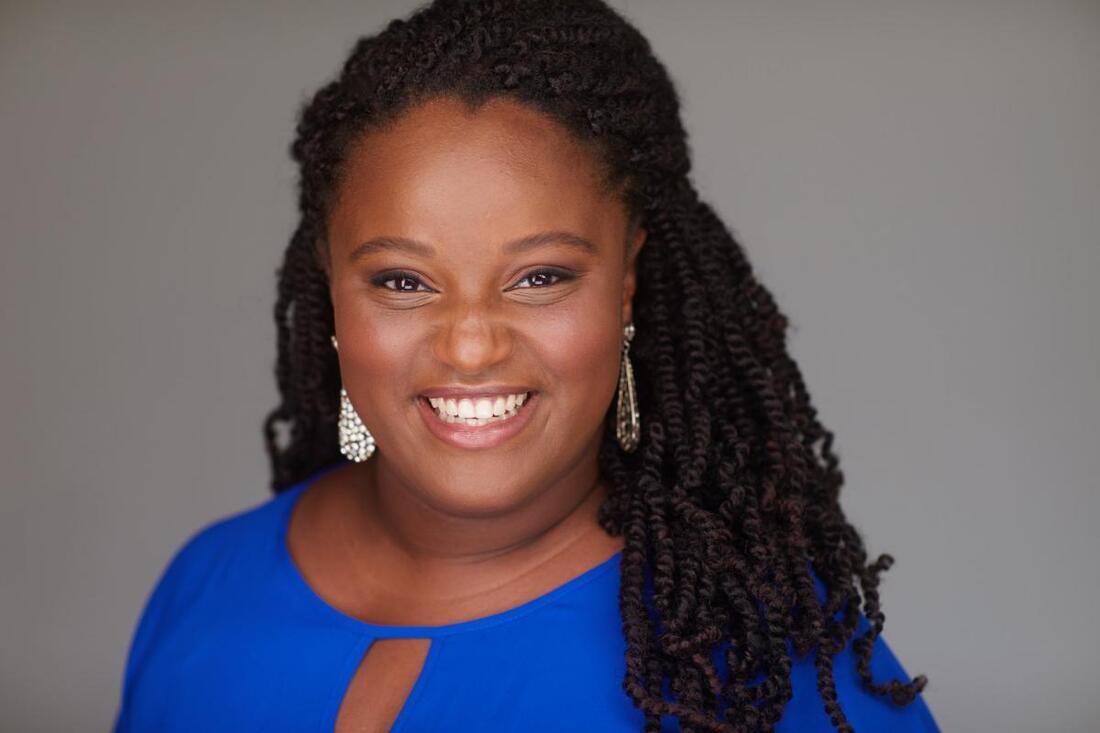 Brianna J. Robinson smiling and wearing a bright blue top.