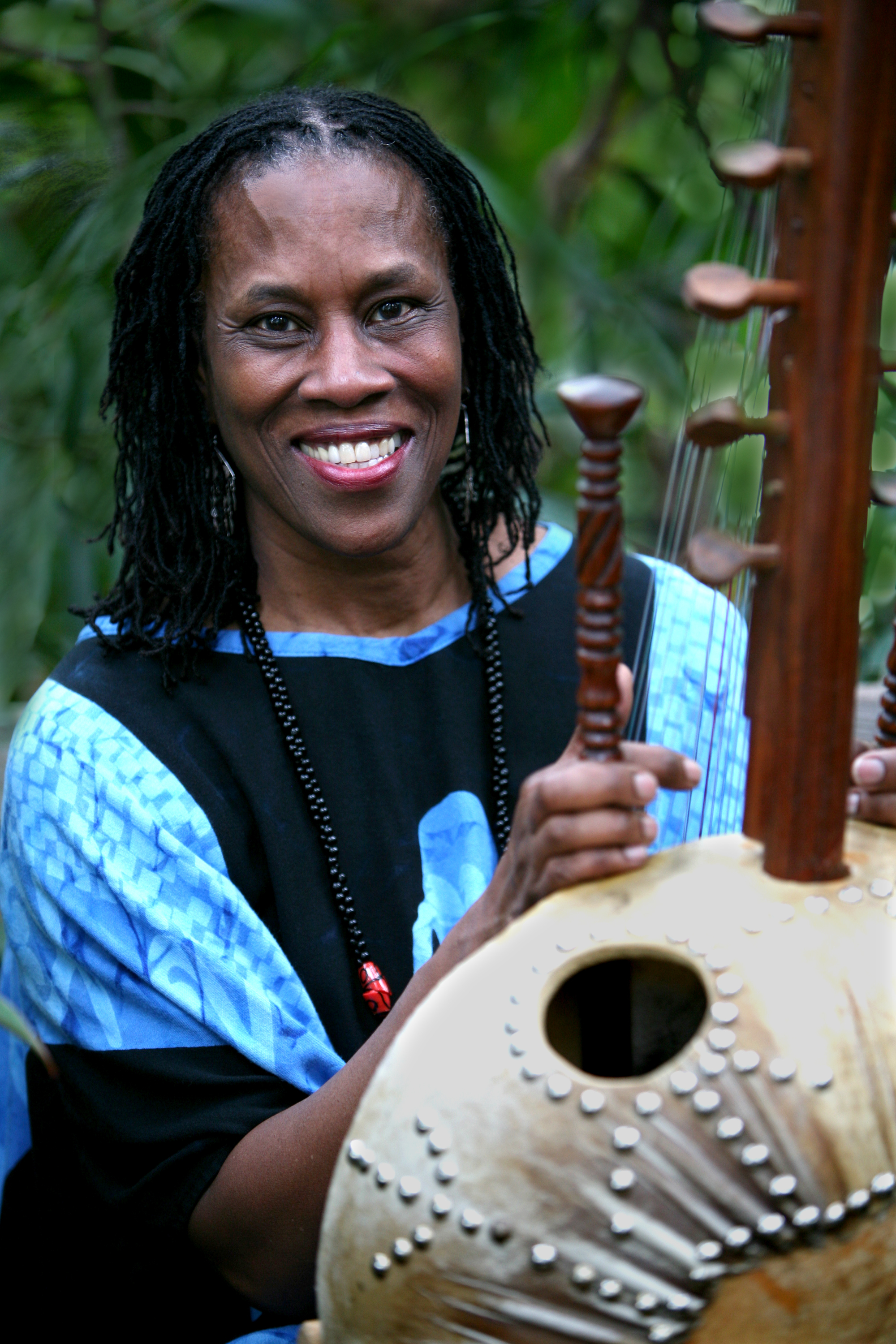 A headshot of Charlotte Blake Alston outdoors holding a Kora