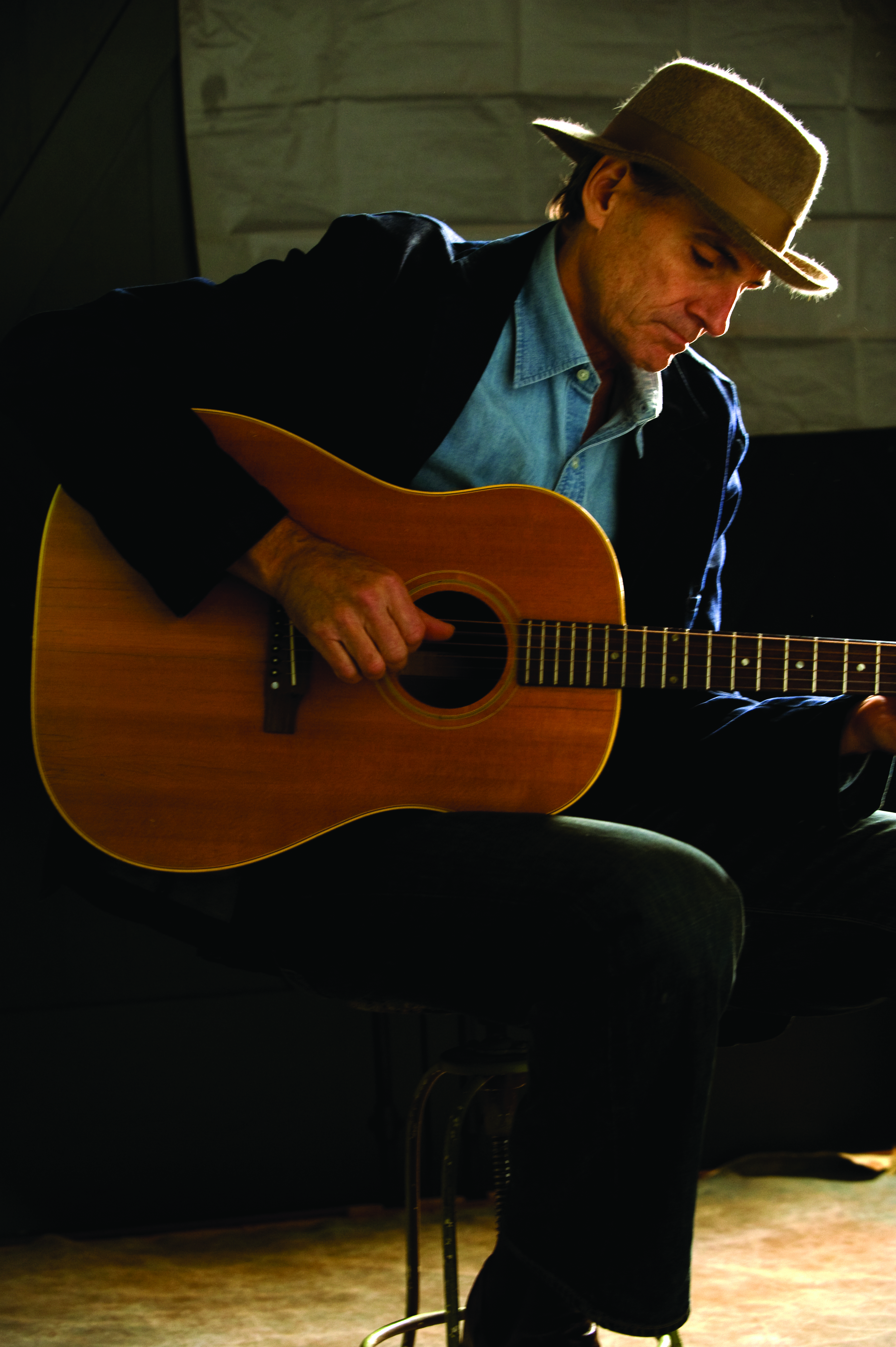 James Taylor sitting down, playing an acoustic guitar