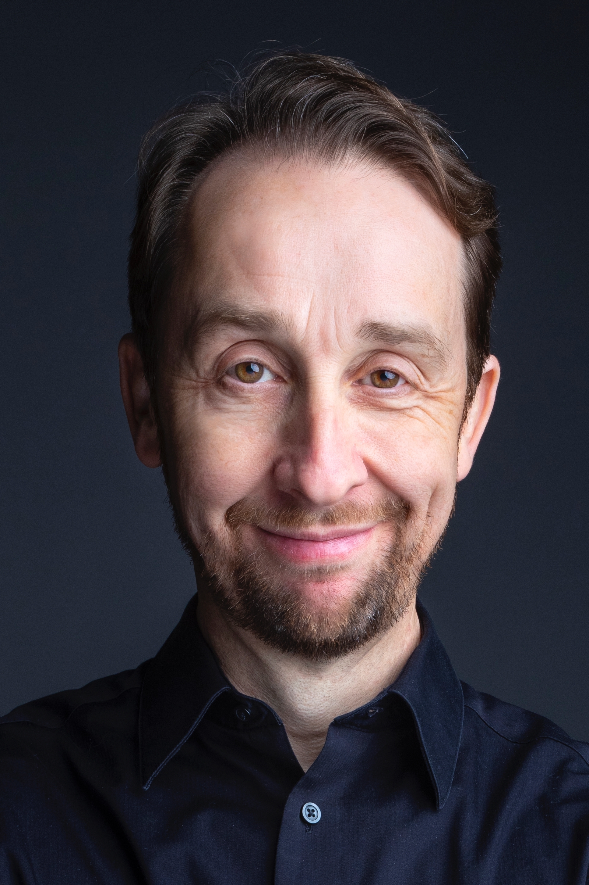 A headshot of David Kravitz looking directly at the camera with a closed mouth smile.