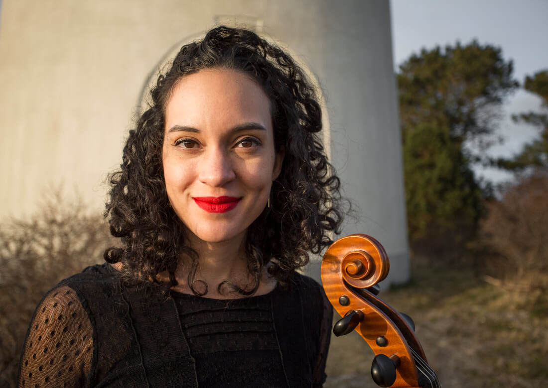 Francesca McNeeley posing with the scroll of her cello visable.