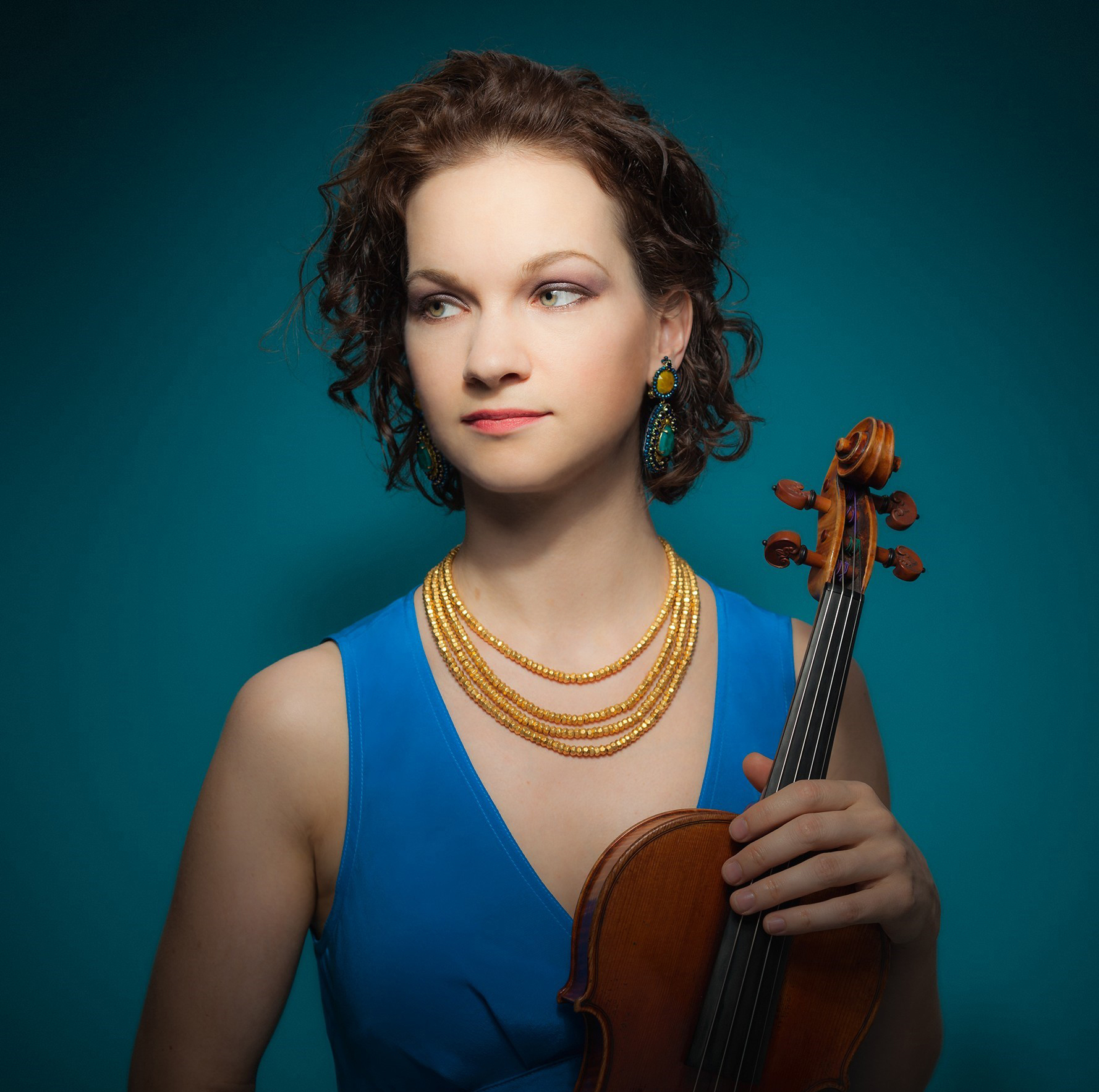 Hillary Hahn holds her violin against a blue background