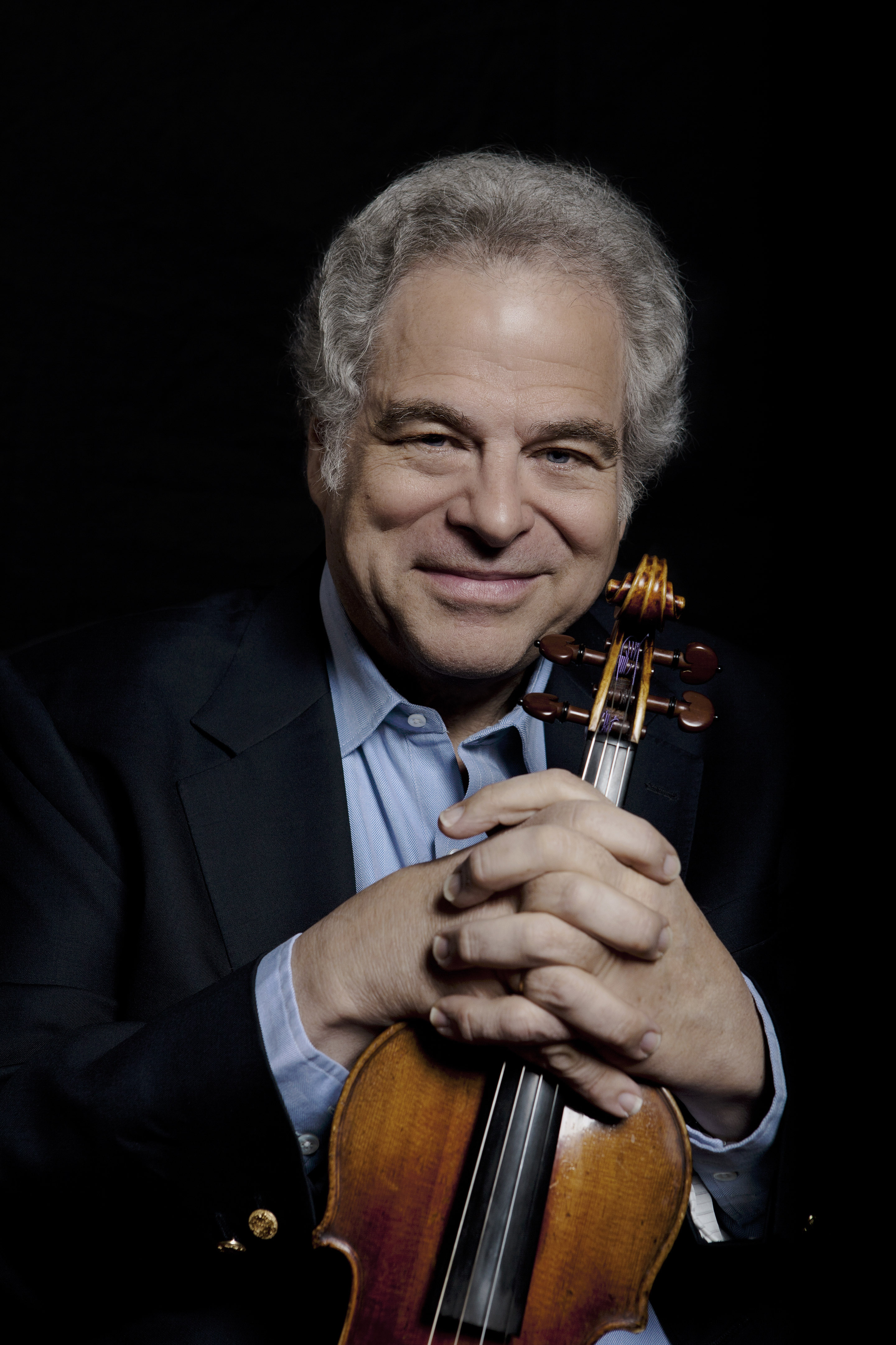 Itzhak Perlman holding his violin and smiling