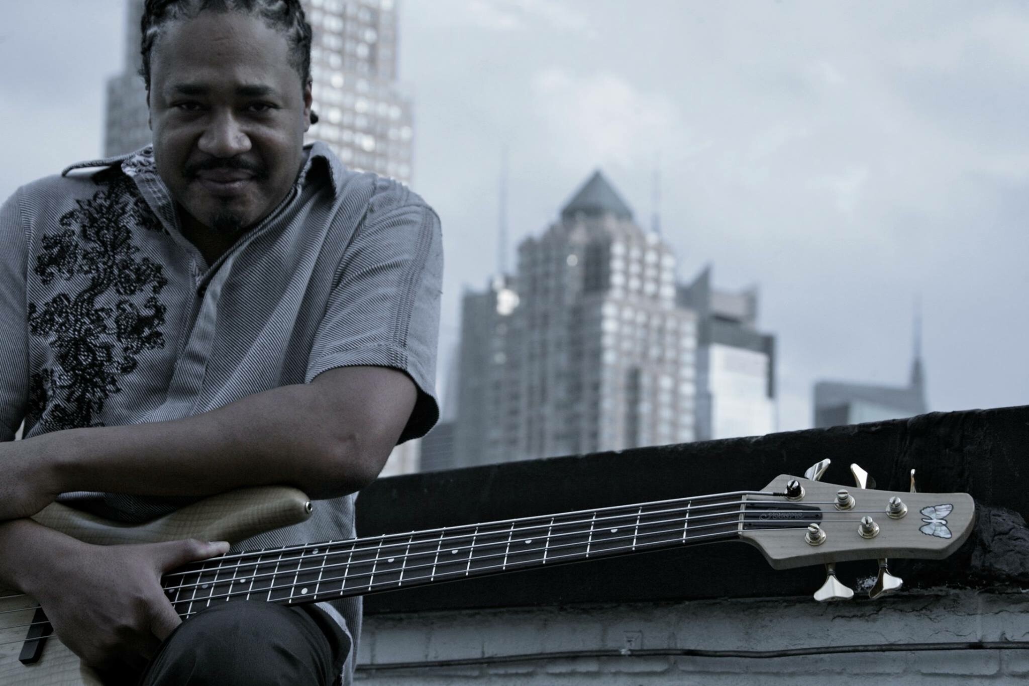 James Genus sitting outside with his bass guitar on his lap