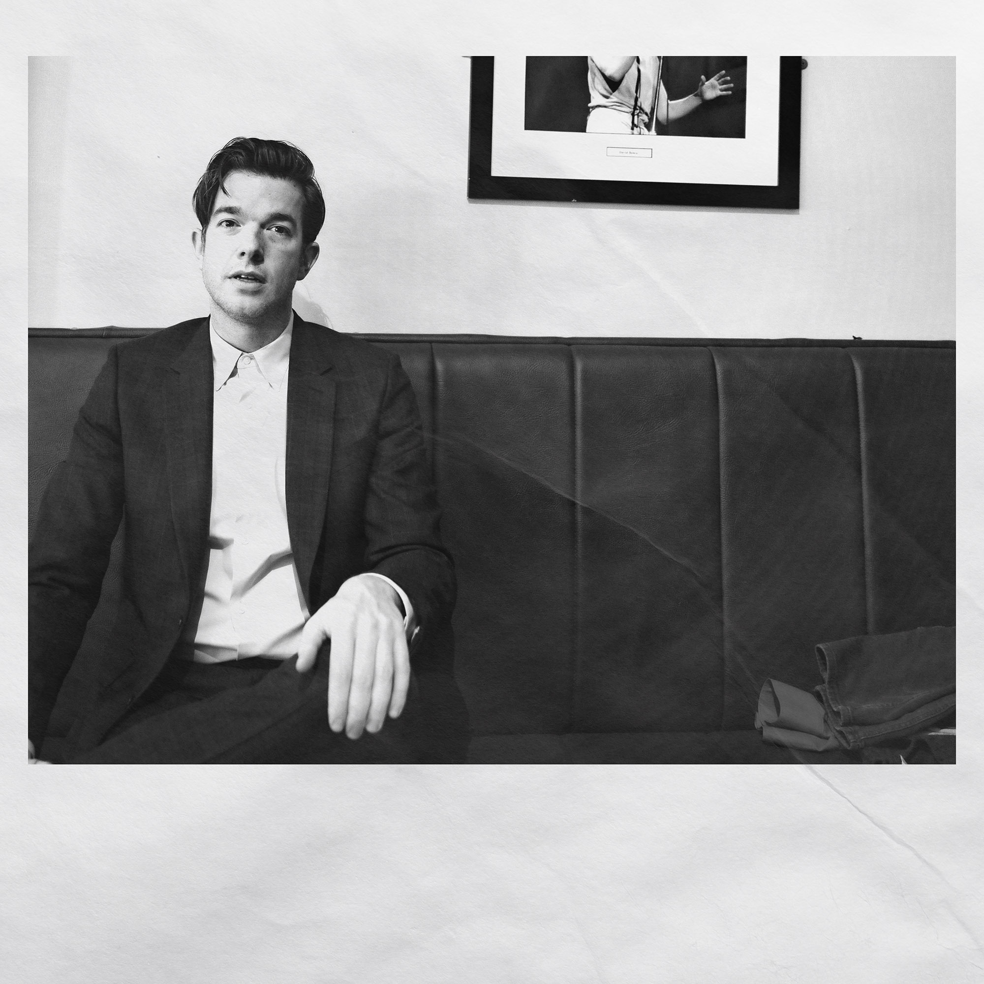 black and white photo of John Mulaney, sitting on a couch