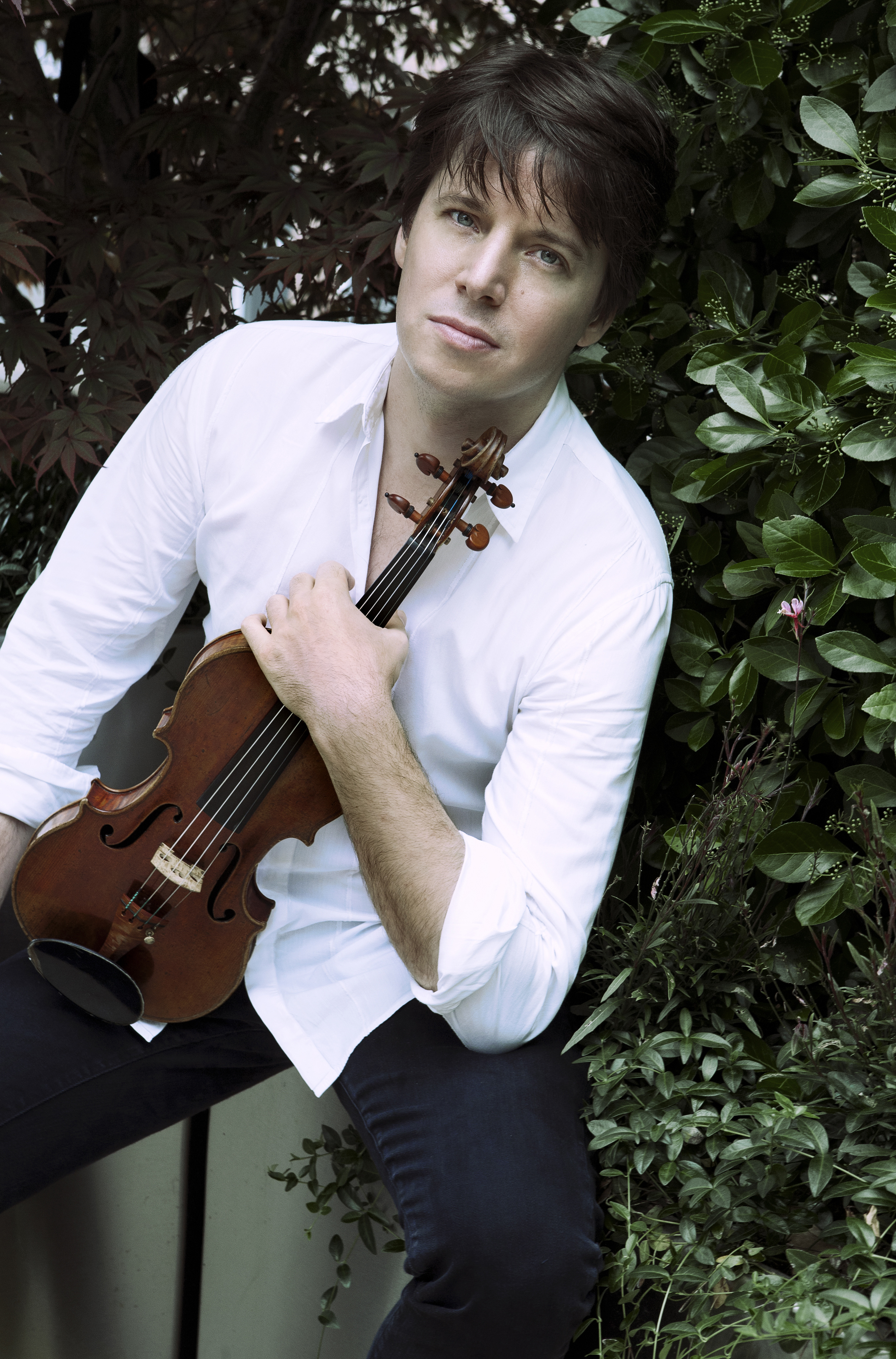Joshua Bell holding his violin while sitting outside