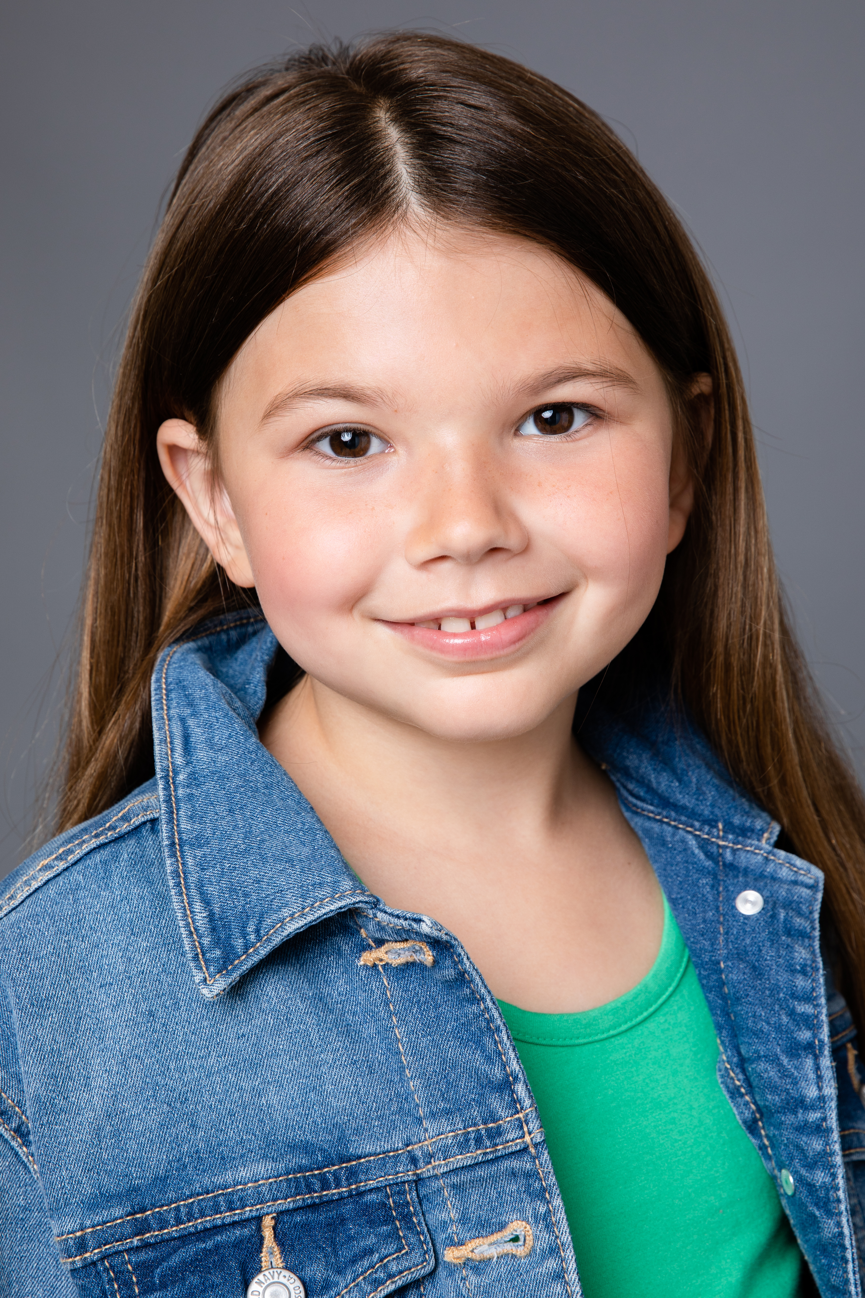 A headshot of Julia Little wearing a jean jacket and green shirt