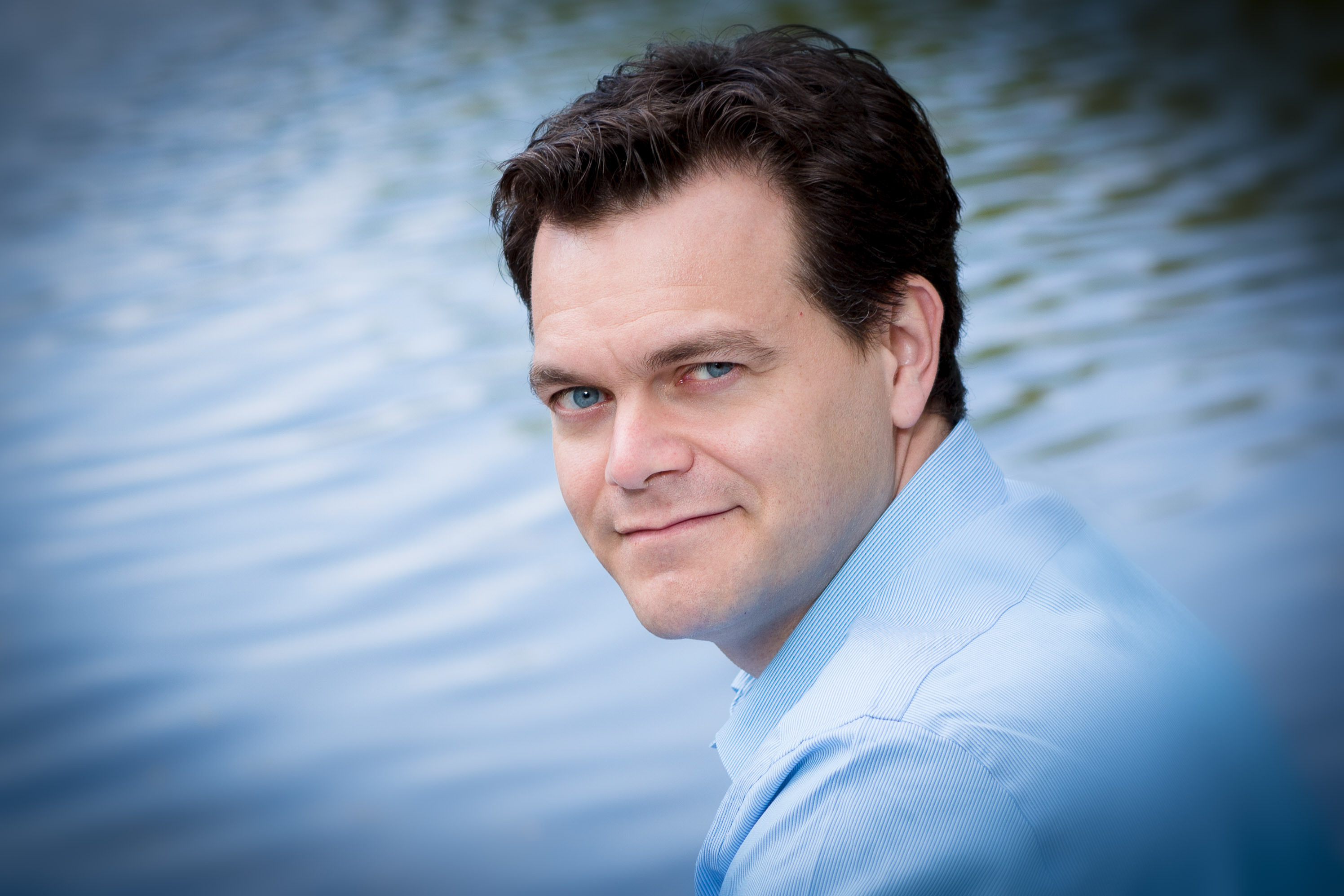 A headshot of Charles Blandy looking over his shoulder in front of water