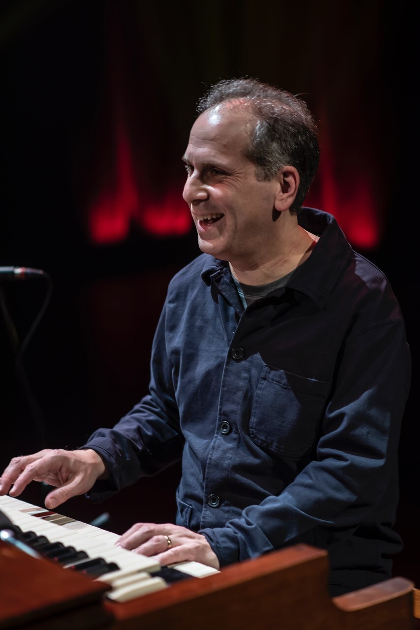 Larry Goldings sitting in front of a piano keyboard, smiling