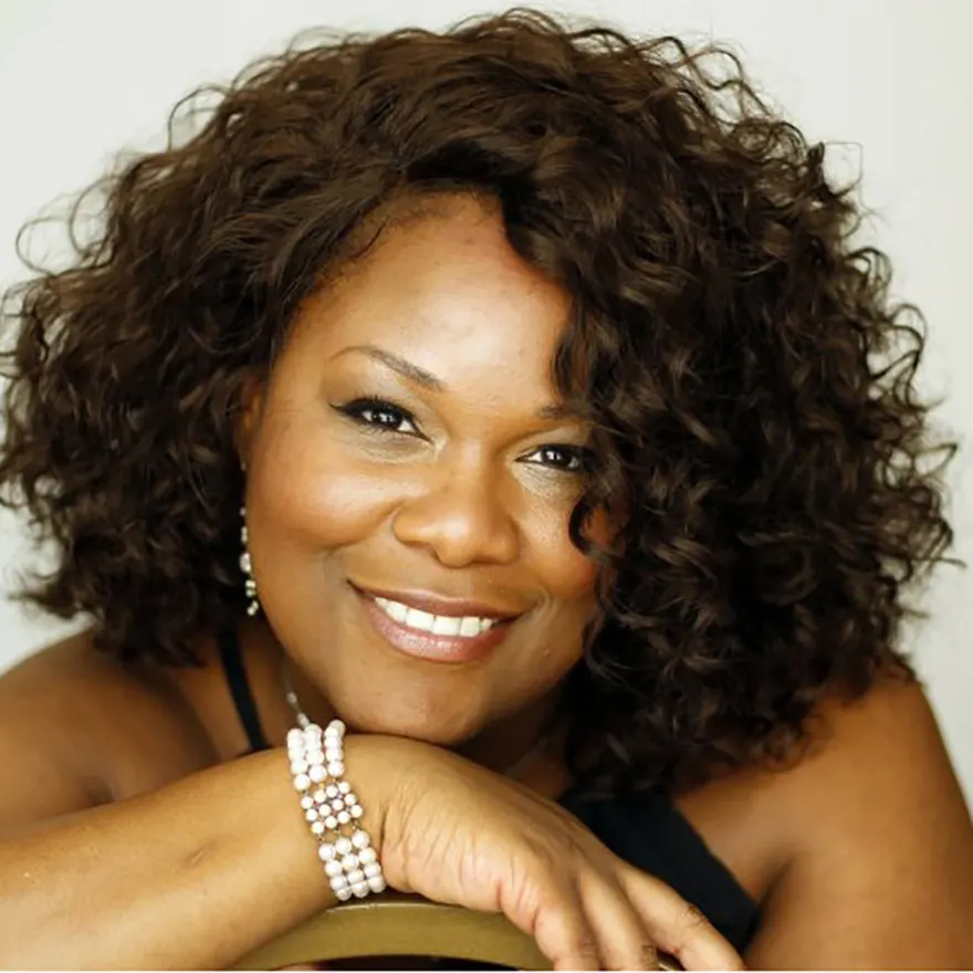 Latonia Moore headshot, smiling with her chin resting on her hands