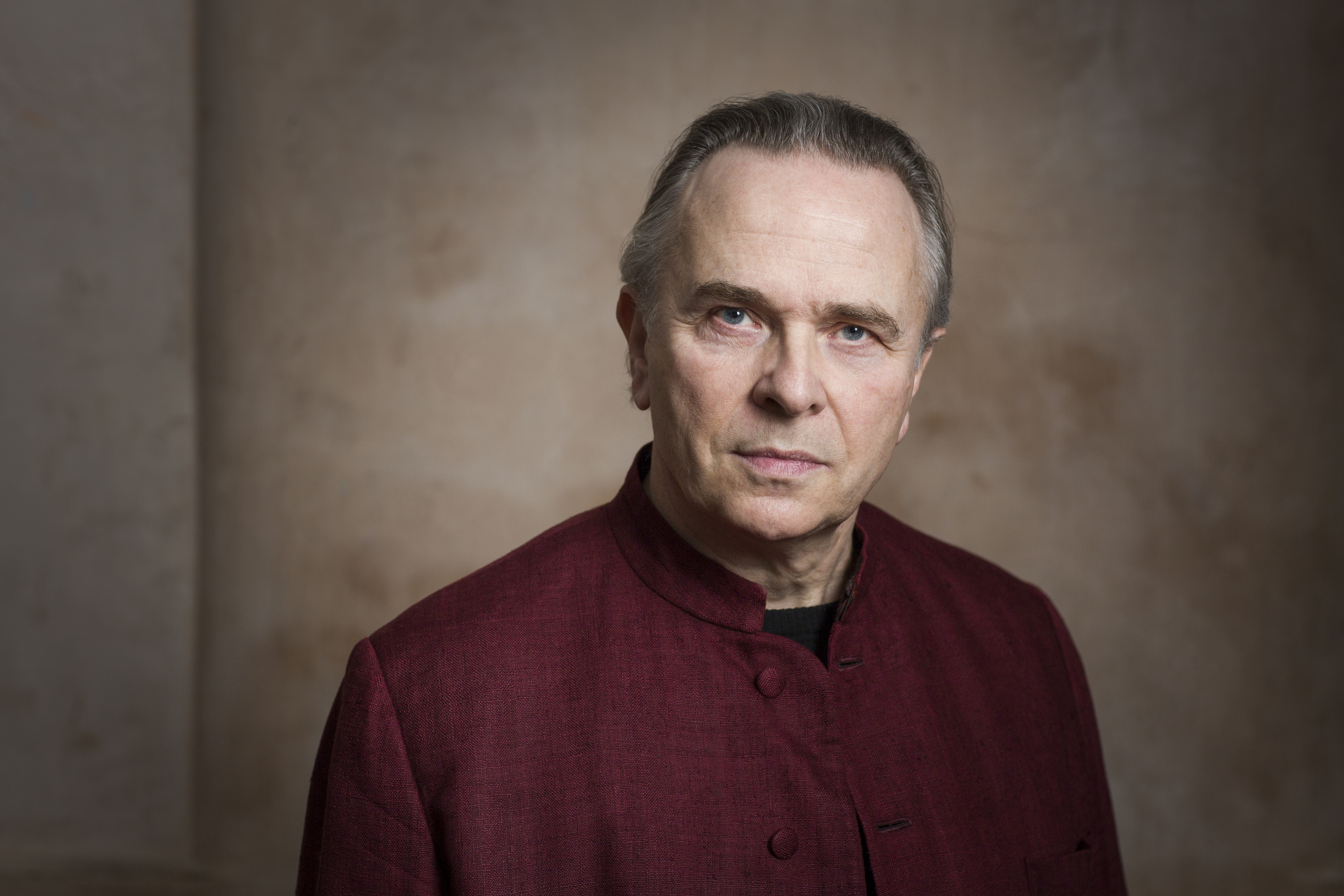 Sir Mark Elder wearing a deep red suit jacket