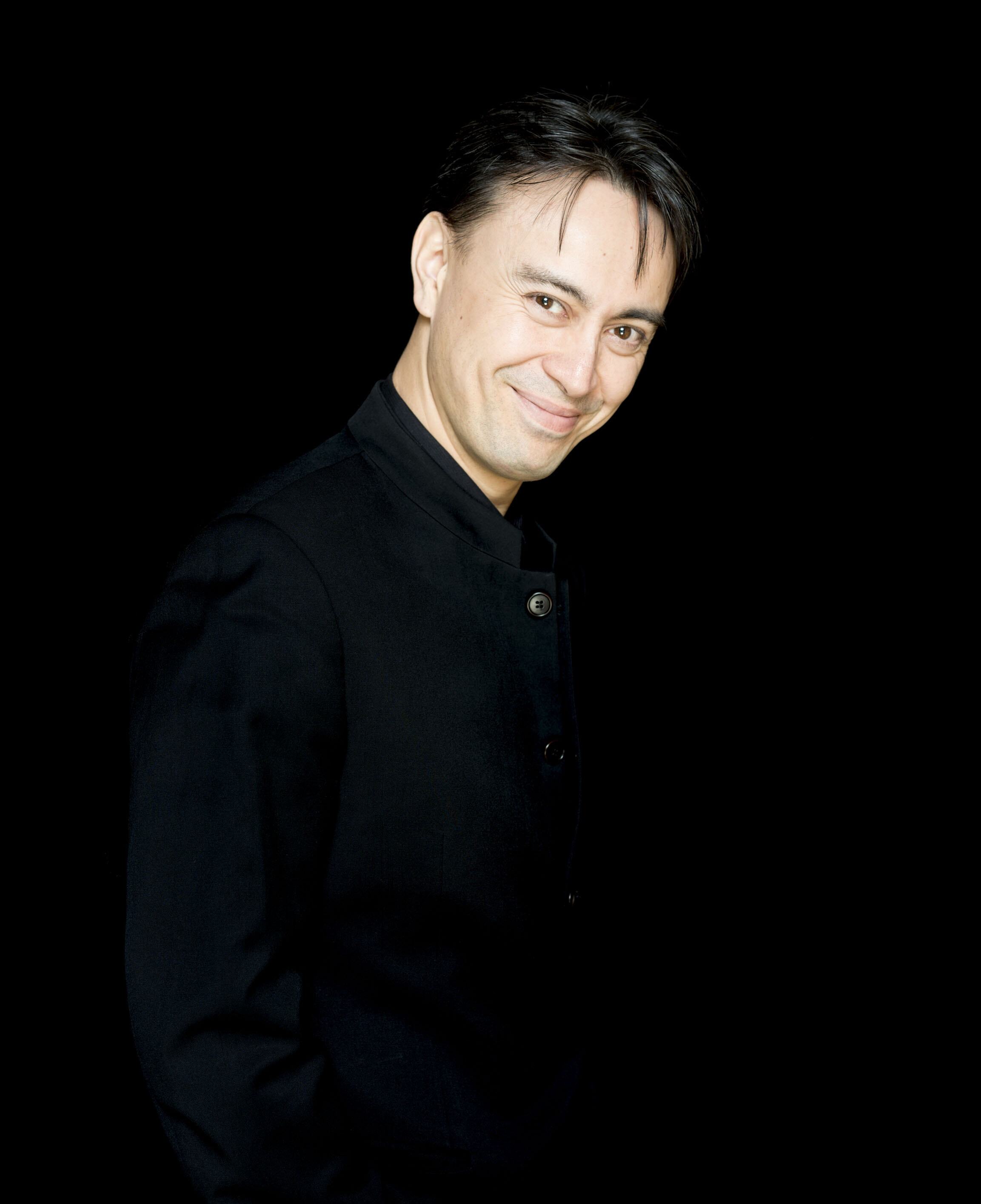 Ken-David Masur smiling while standing in front of a black background