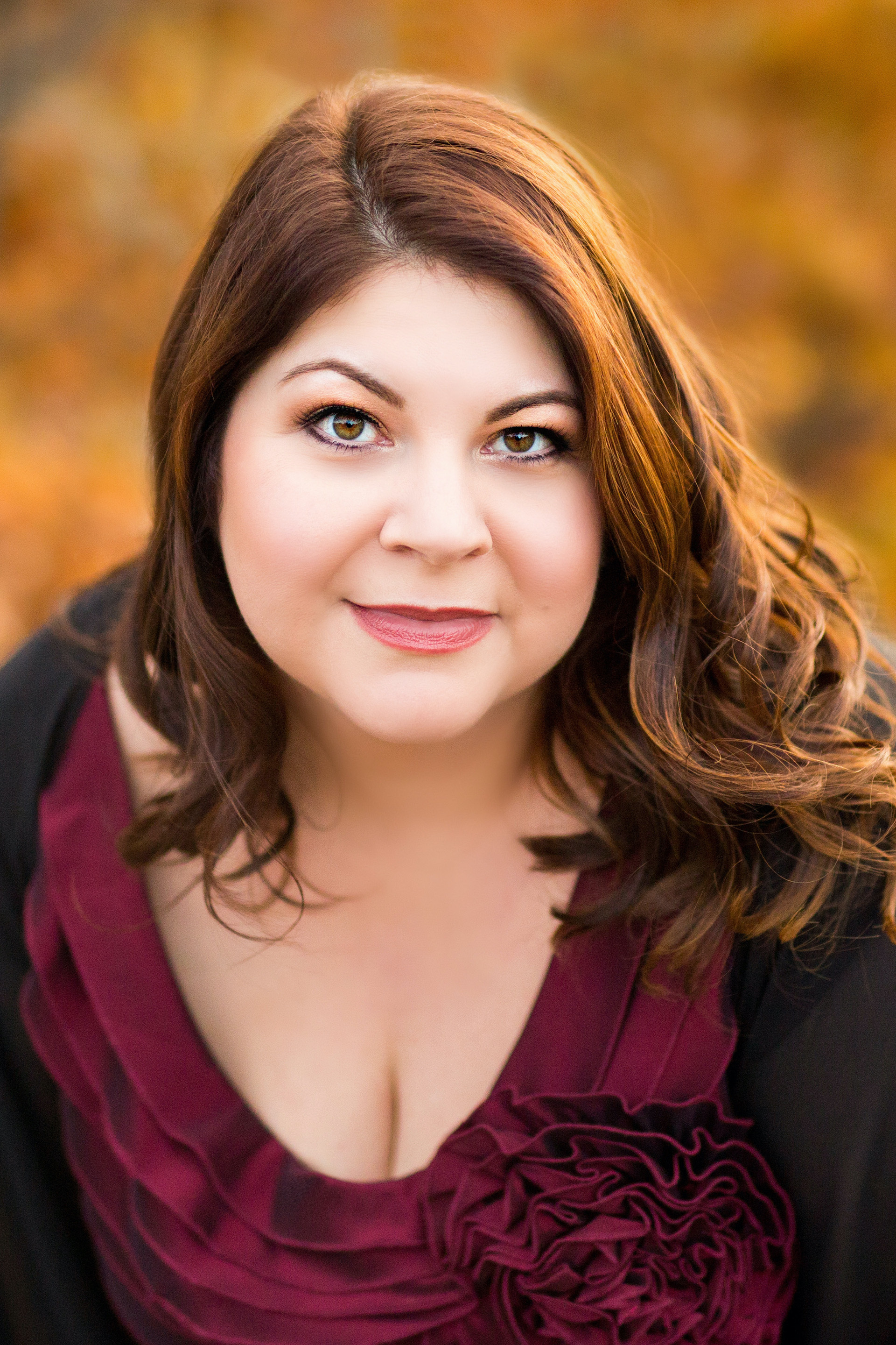A headshot of Michelle Trainor with a background of fall colored leaves
