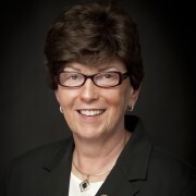 Headshot of a smiling woman wearing glasses and a dark blazer
