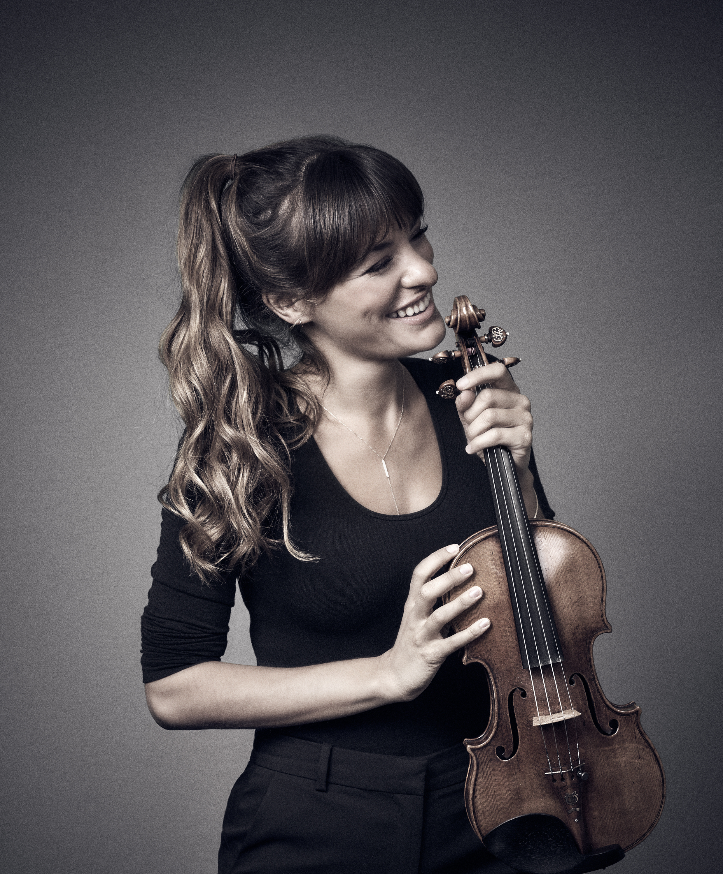 Nicola Benedetti smiling, looking to her right and holding her violin