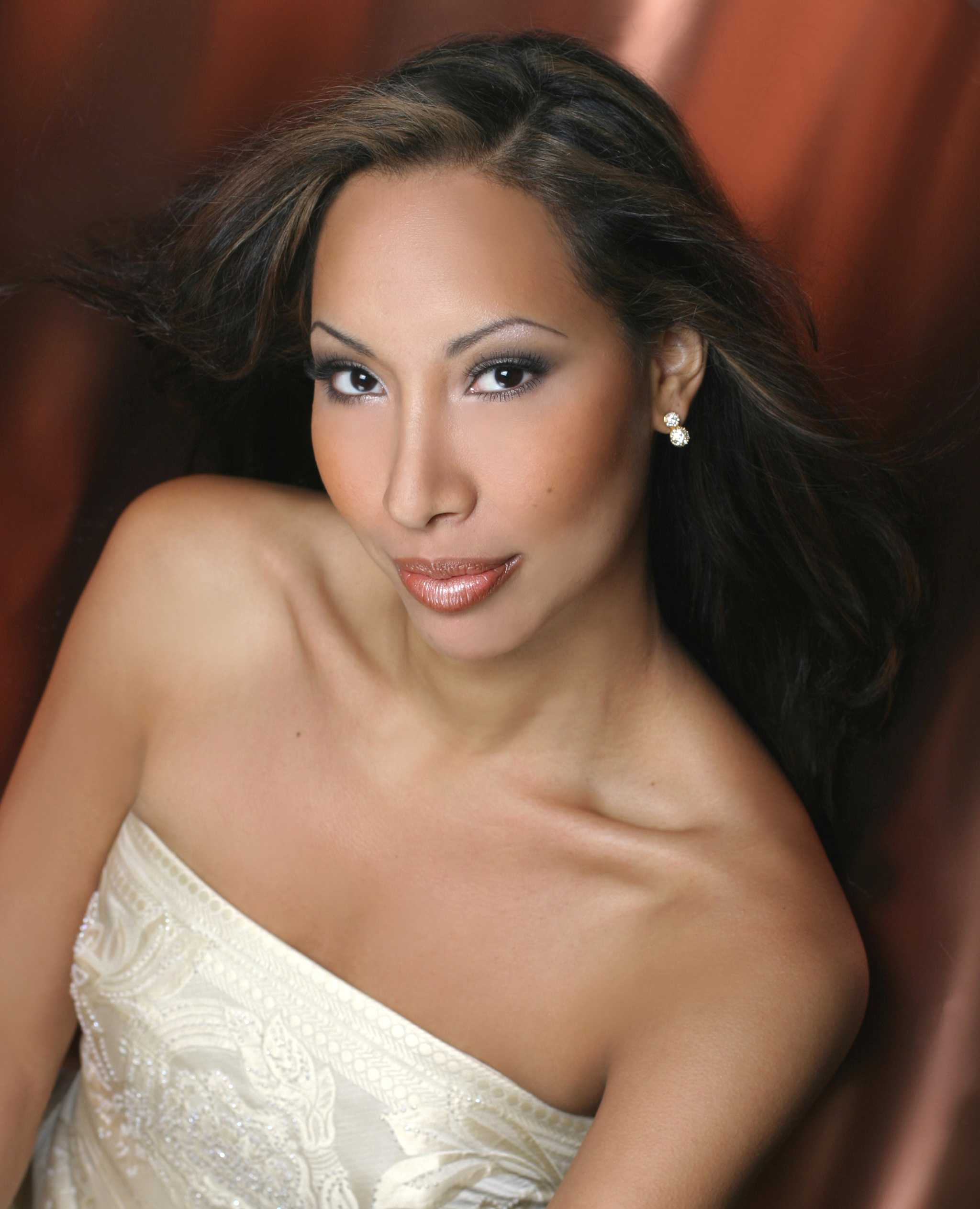 Nicole Cabell in front of a brown background, wearing an ivory gown