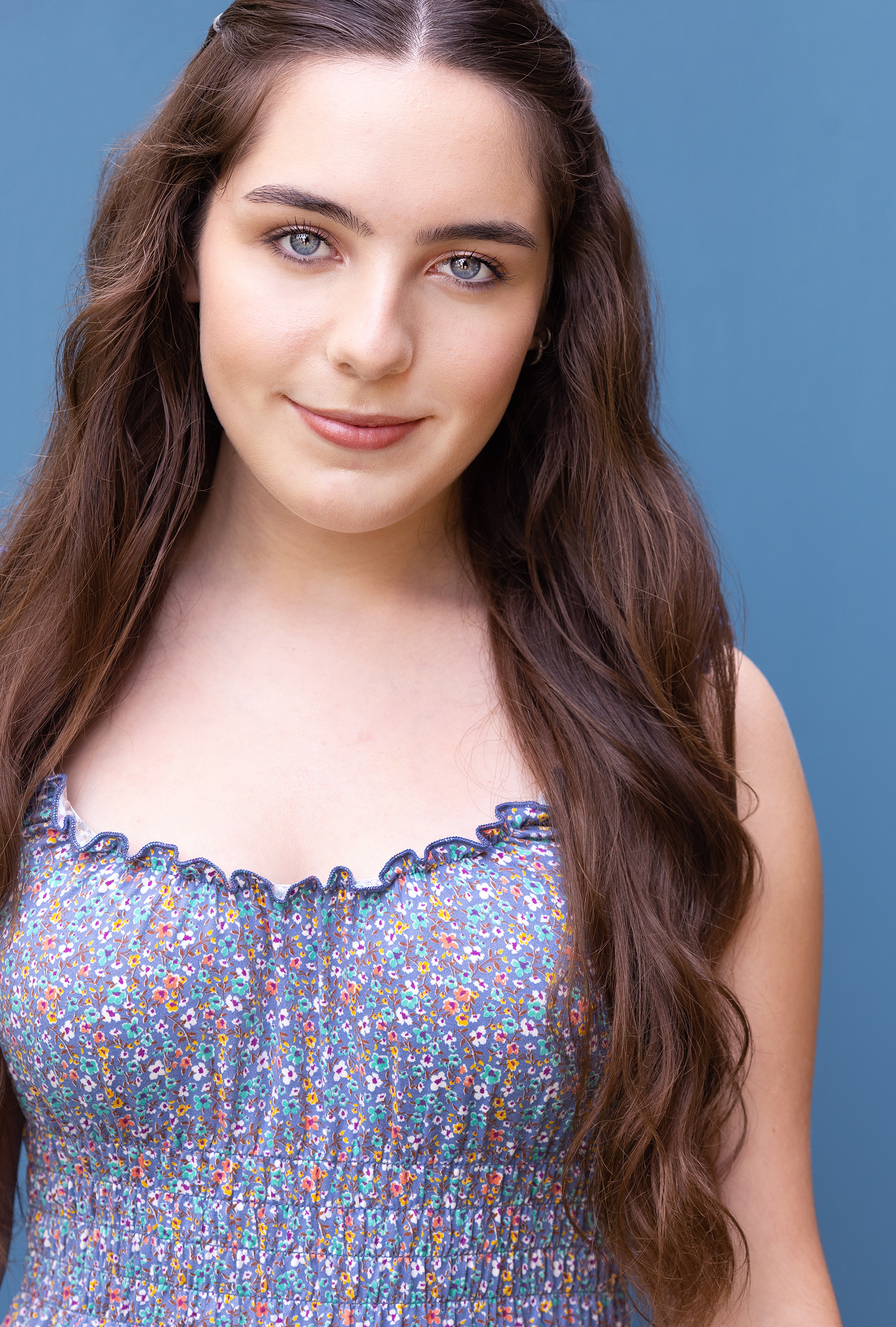 A headshot of Juliet Simon wearing a multicolored speckled blouse