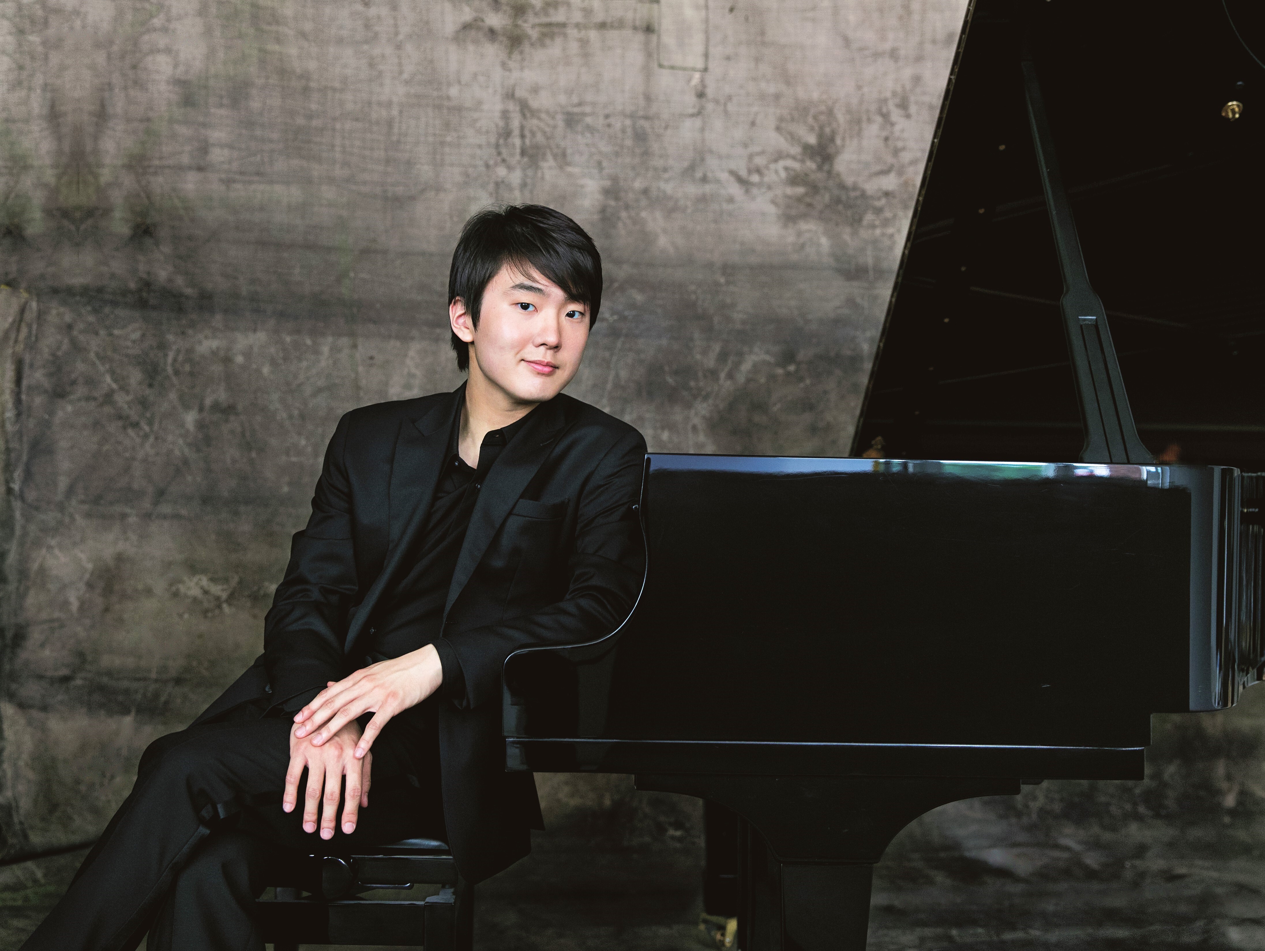 Seong Jin Cho sitting in front of a piano