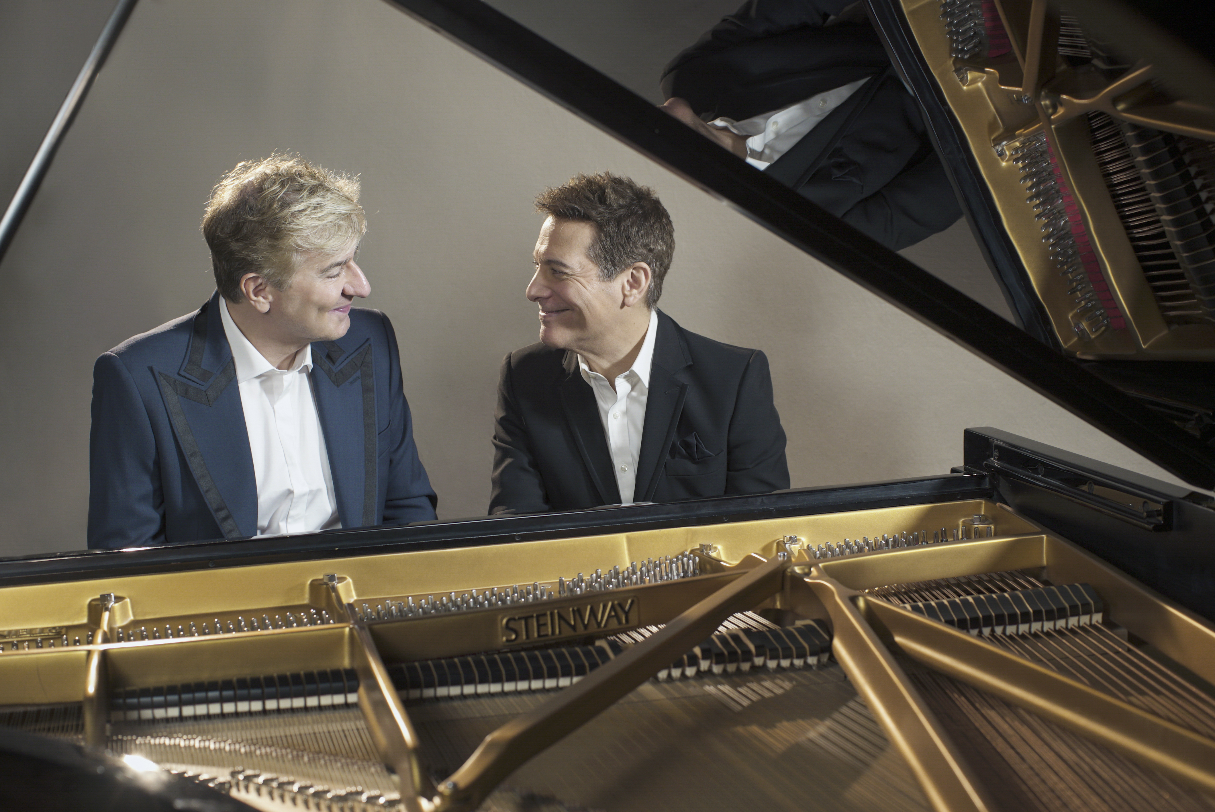 Jean-Yves Thibaudet and Michael Feinstein sitting in front of a piano, smiling at each other
