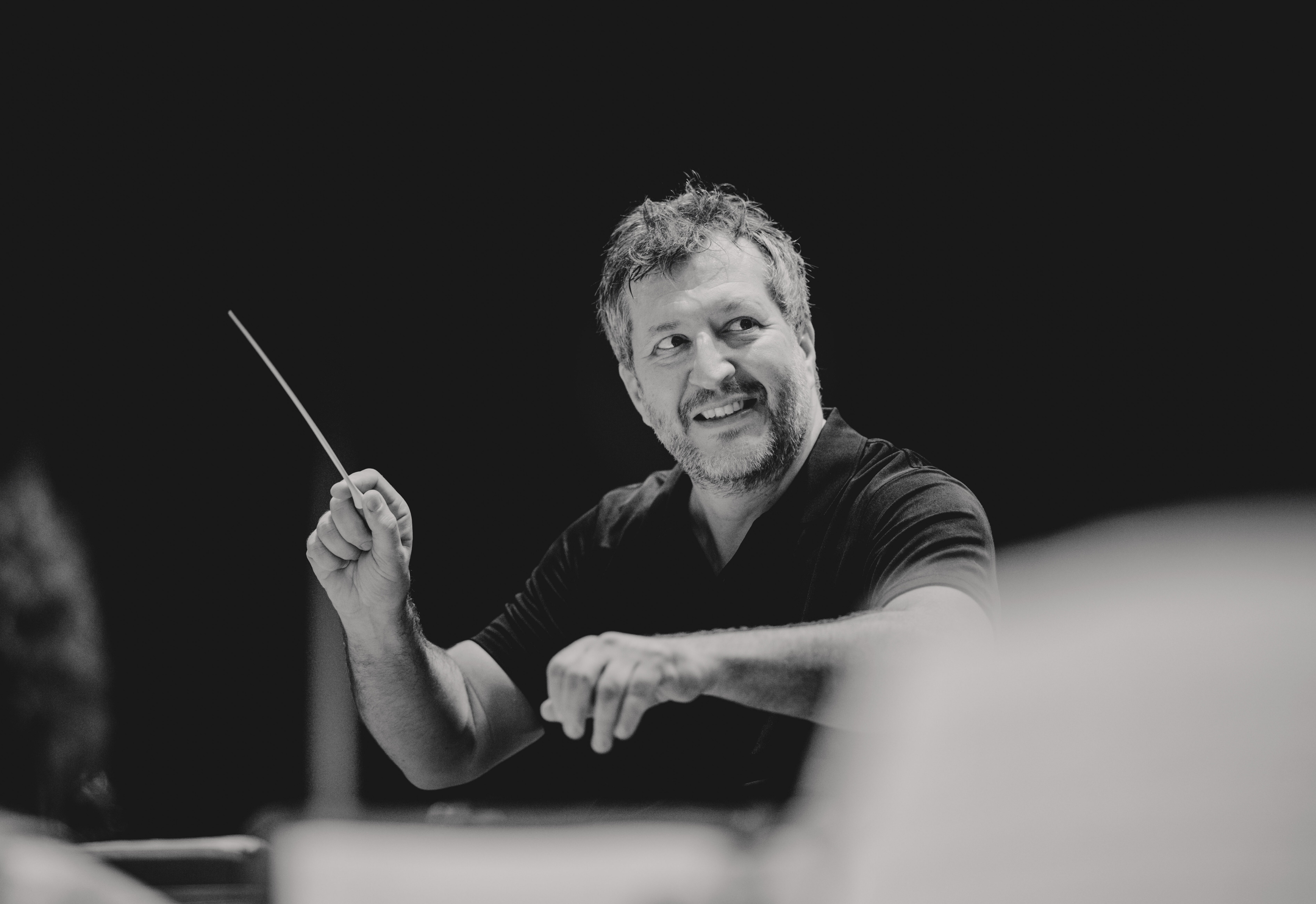 Thomas Adès with a large smile while conducting