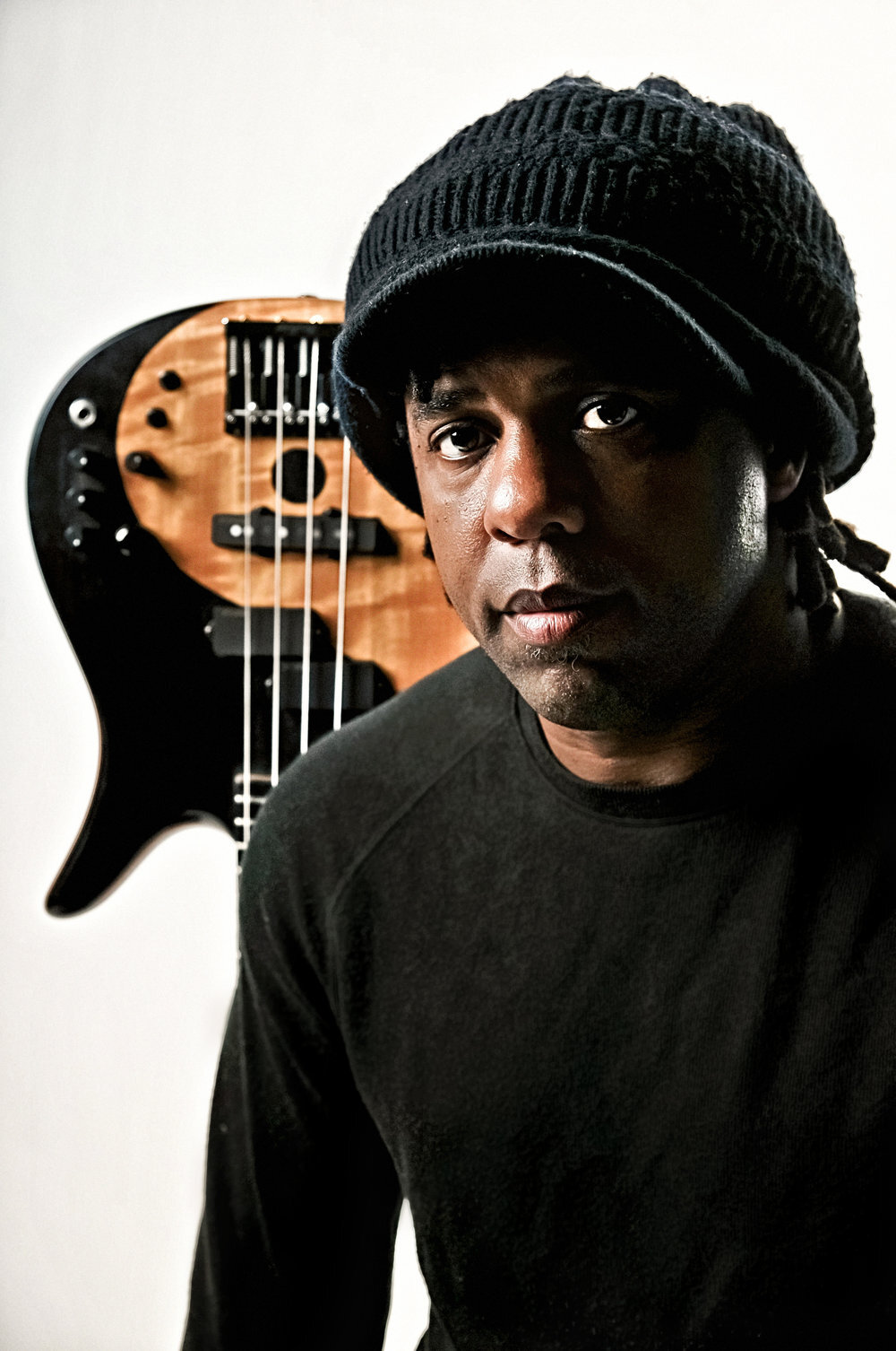 Victor Wooten sitting in front of an upside-down electric bass