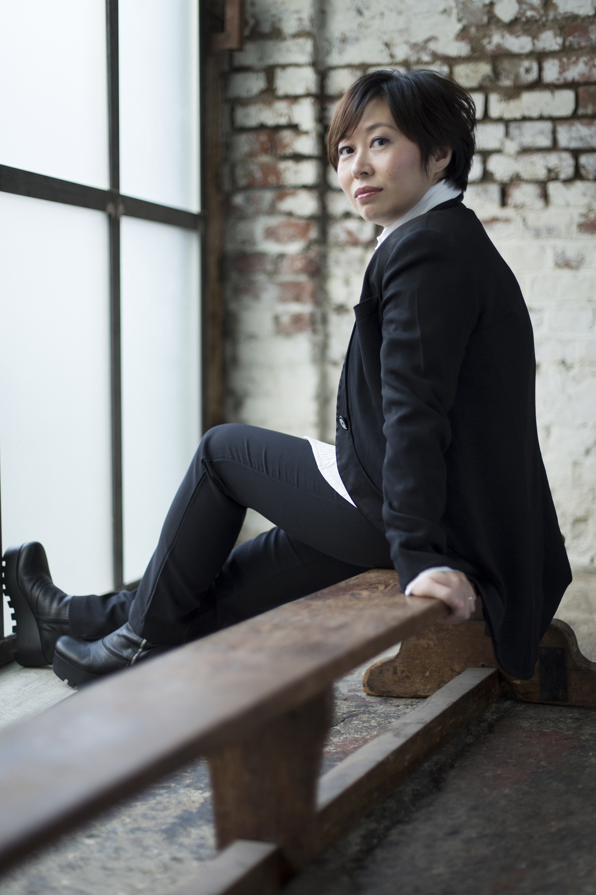 Xian Zhang sitting on a bench in front of a window