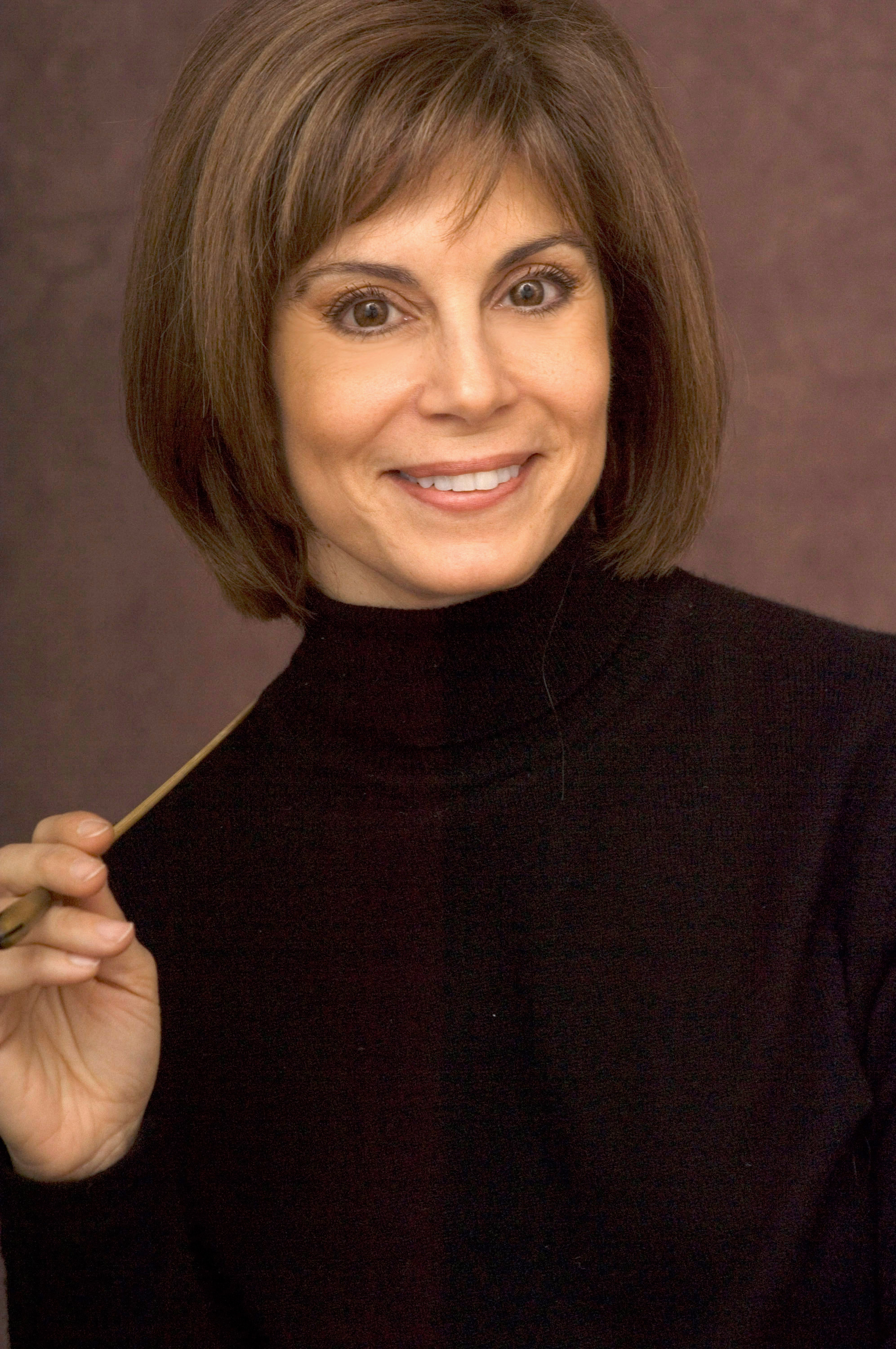 Headshot of JoAnn Falletta in a black turtleneck holding her baton